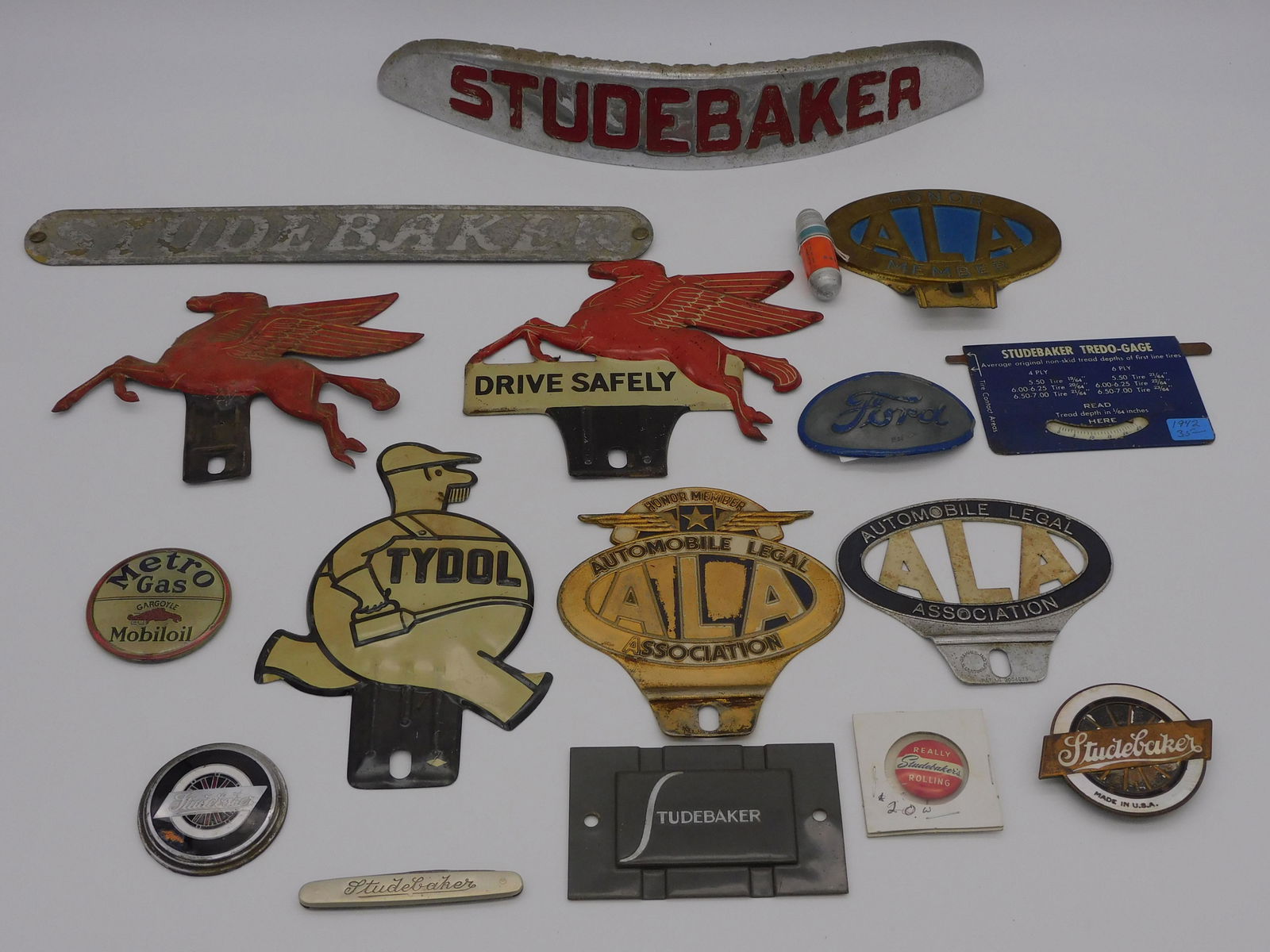 (17) Studebaker and auto lot, to include: a: chrome name tag from a Studebaker, 14" x 2 1/2" high. Studebaker jack knife, 3". 2 Studebaker metal emblems, possibly a wheel or grille mount, one is 2 1/4" diameter, the other is 2" diameter. A Stude