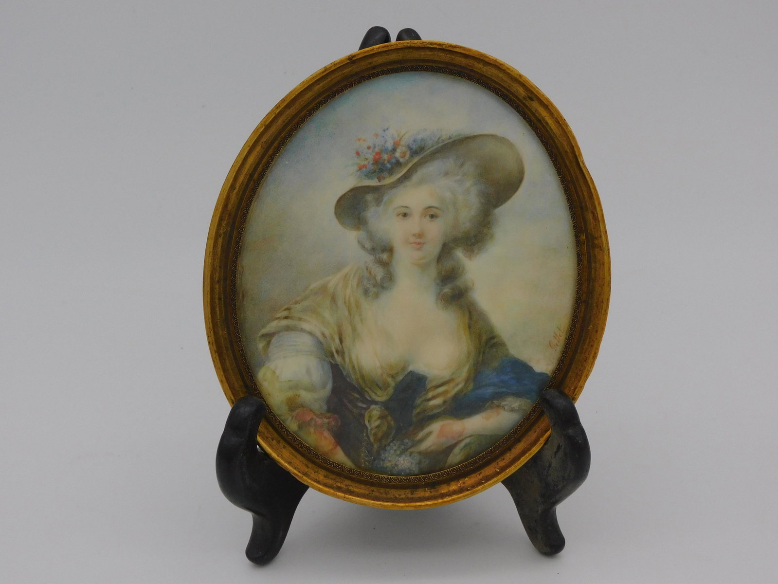 Miniature portrait of a fashionable young woman,: late 18th c. Signed Gellet. In a period gold oval frame. 5" x 4". Identified illegibly on verso. Slight discoloration on her arm.