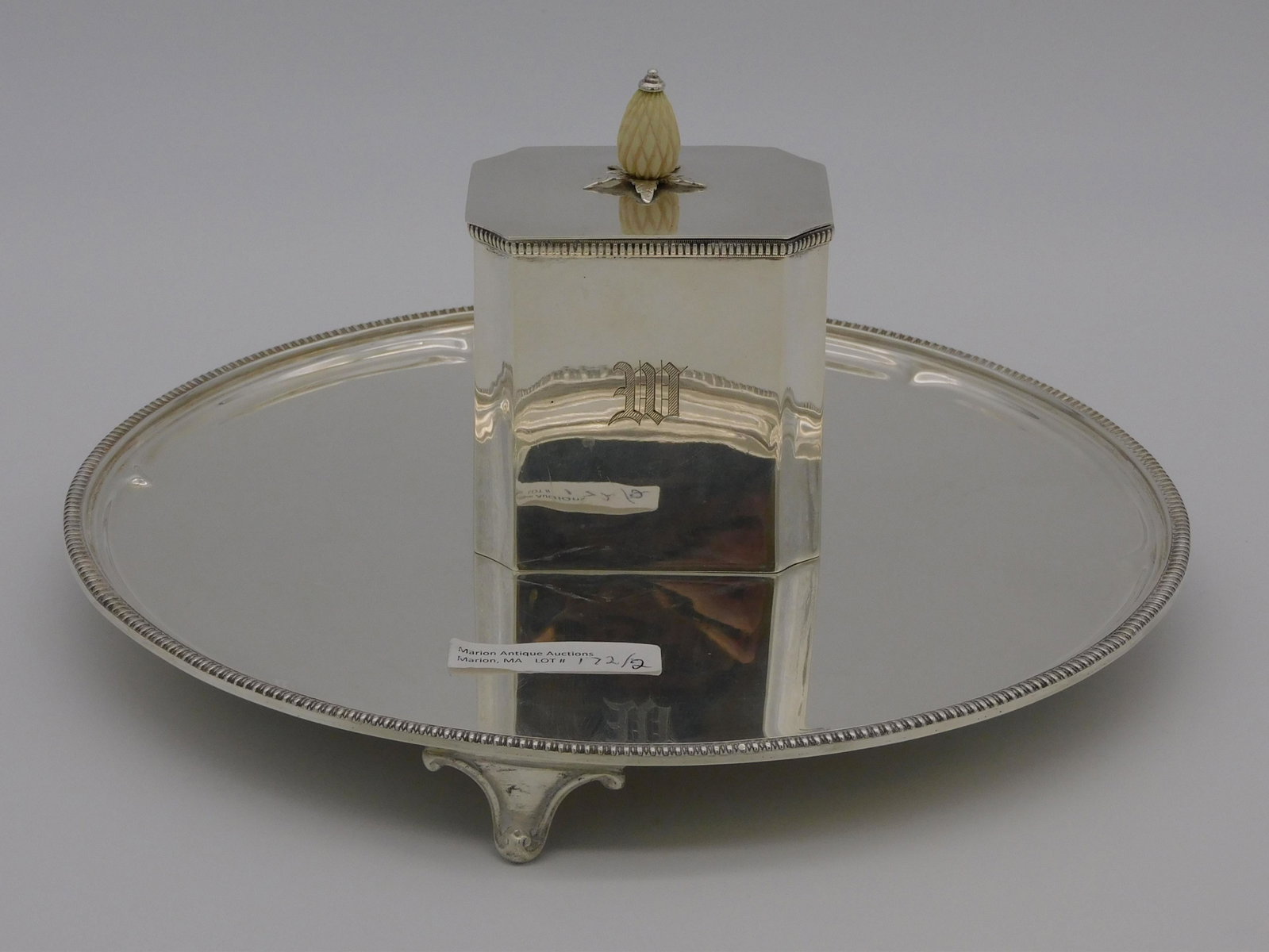 (2) Sterling Silver Pieces, 20th century. An: English footed tray by T. and Company, Sheffield, 1" high, 10" diameter. A handmade sterling silver tea caddy with a carved pineapple finial and monogram, 4" high, 2 5/8" wide, 2" deep. 24.83 total oz