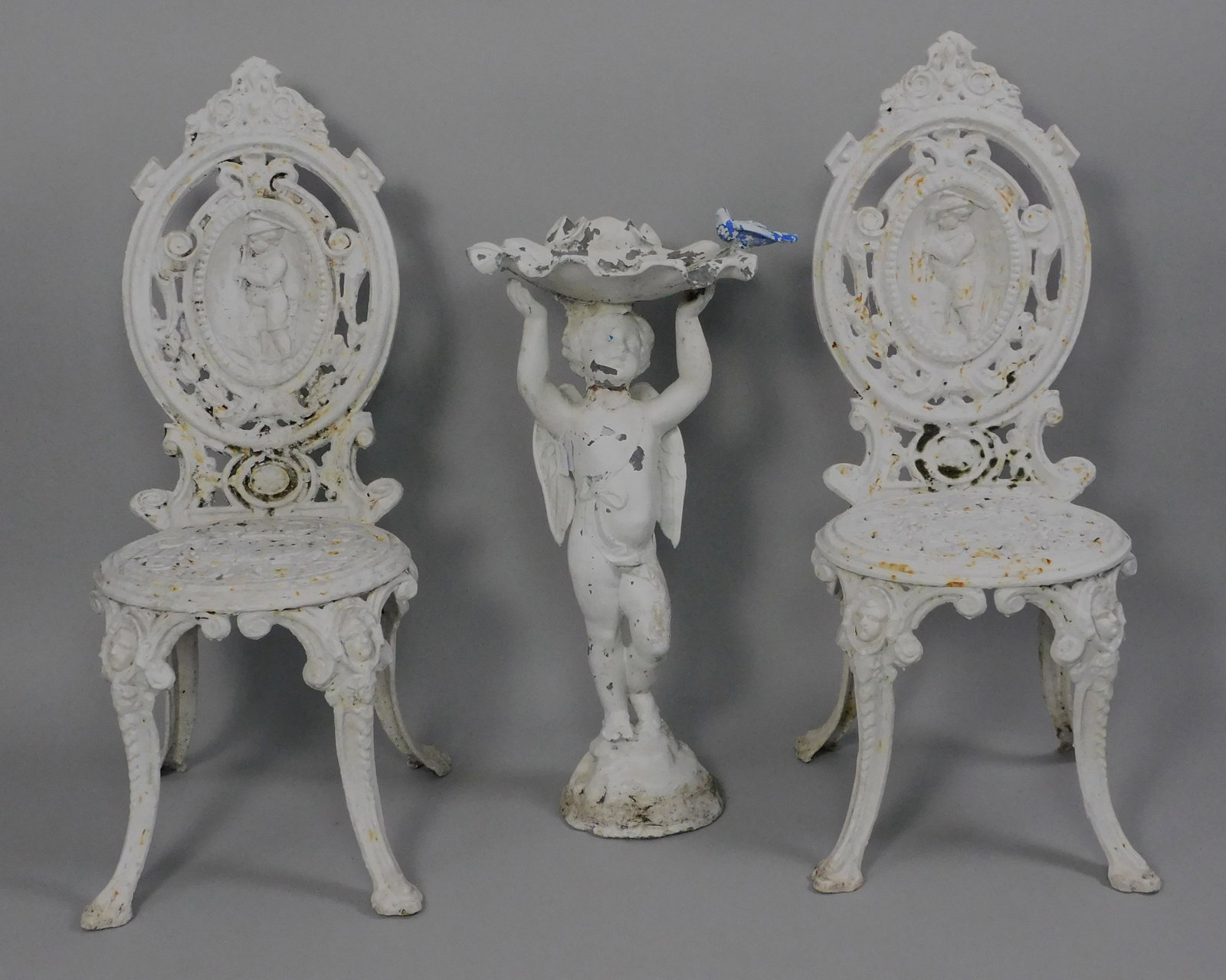 Victorian garden furniture, Late 19th c. To: include: pair of matching side chairs with four season design, possibly by Coalbrookedale, 38" high, 15 1/2" wide, 17 1/2" deep. Along with a cast zinc birdbath of winged cherub supporting a shell for