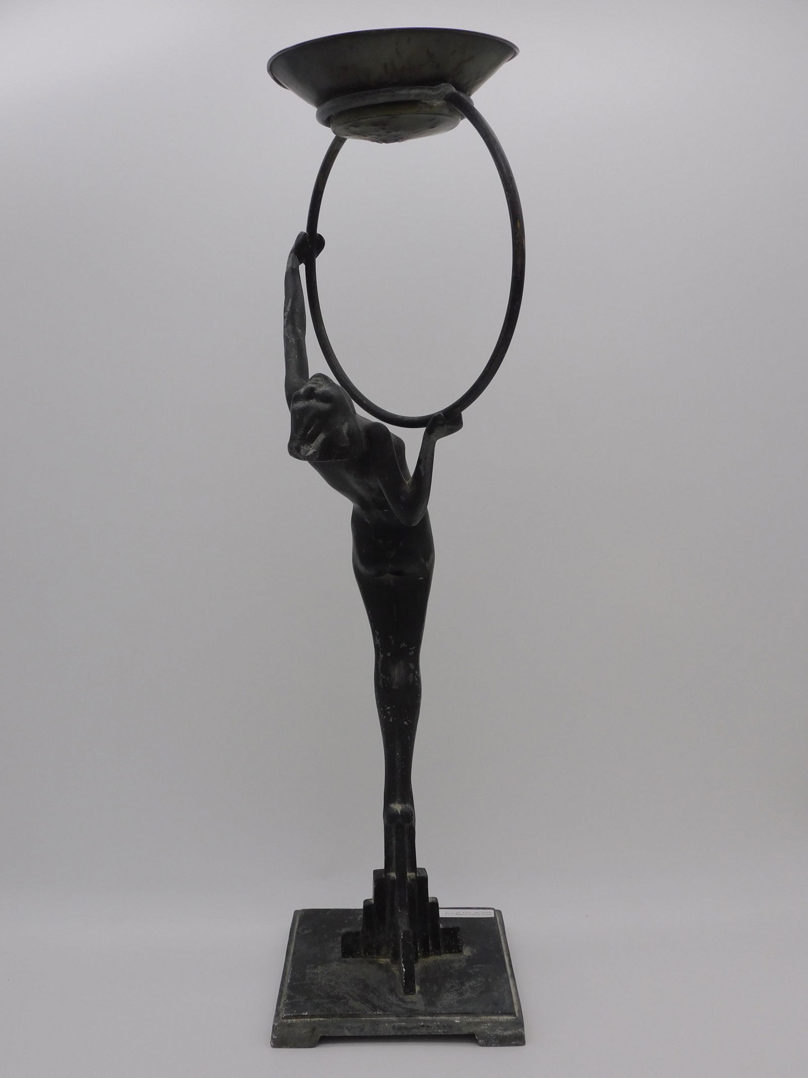 Frankart signed Art Deco smoking stand, depicting: a standing nude woman holding a ring that supports an ashtray. Early 20th c. Missing glass insert. 25 1/2" tall, base is 6 5/8" x 6 7/8". Old black painted finish.