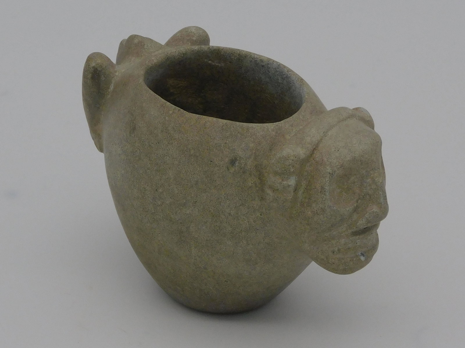 Taino, small figural stone lime vessel with: anthropic head on front, and legs on opposite side. Pre-Columbian. The bowl is ovate. Possibly contained lime to mix with cohoba. Lime helped to neutralize digestive stomach acids that reduced the hal