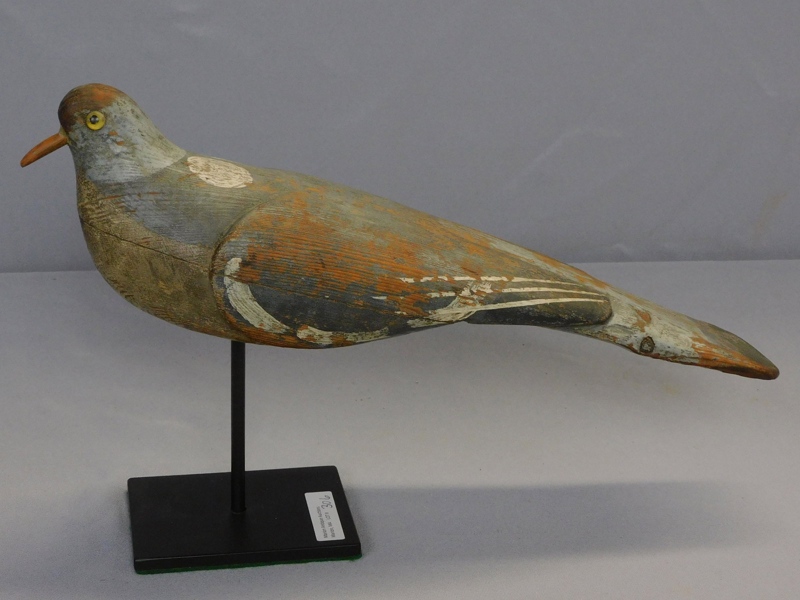 Carved and painted pigeon decoy, early 20th c.: Glass eyes, on a metal stand. 14" long. Original painted finish shows overall wear.