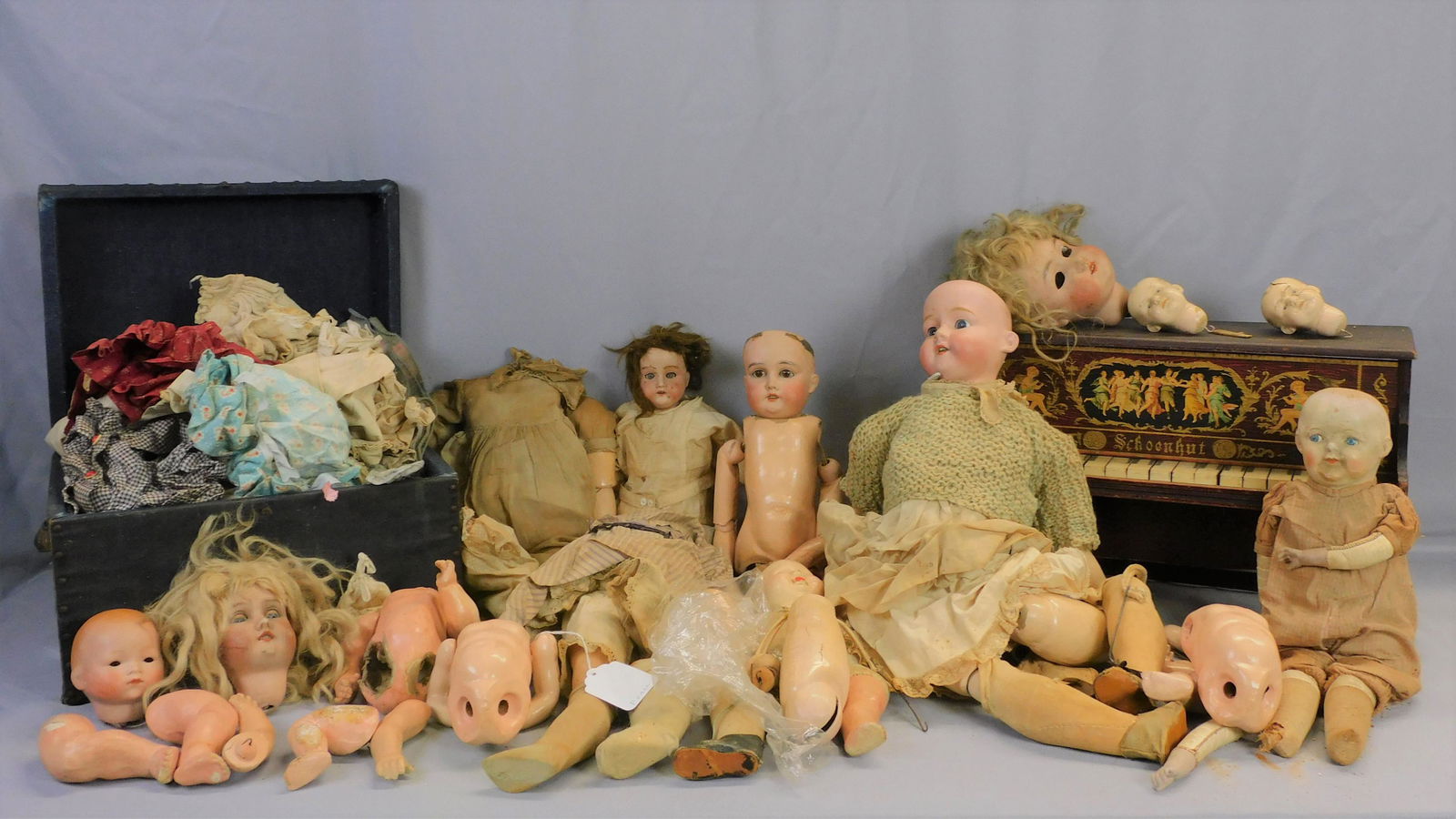 Large lot of vintage dolls, parts, clothes,: trunk, and Schoenhut piano. Composition bodies, pieces, remnants, bisque heads. Piano is 12" high, 19" wide, 8" deep, original finish. Trunk is 9 1/2" high, 15" wide, 11" deep. Doll height range. Seve