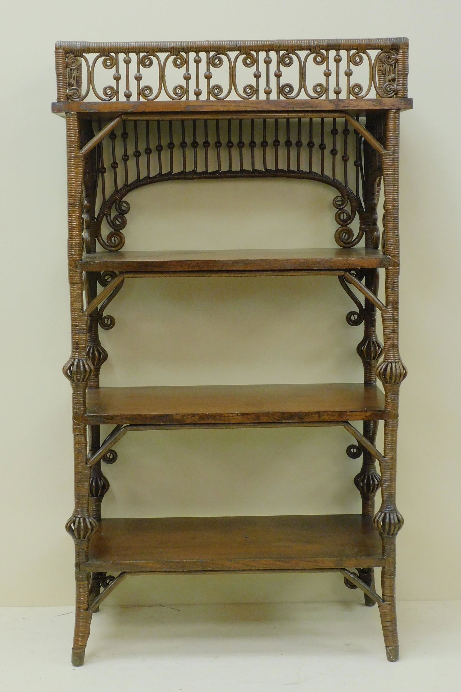 Victorian wicker etagere, ca. 1898, Heywood Bros.: Wakefield Co., #6443 in the 1898 catalogue where it is listed as a fancy cabinet. It has 4 quartersawn oak shelves, curlicue and stick and ball galleries. Birdcage trim on legs. Old natural finish. 46
