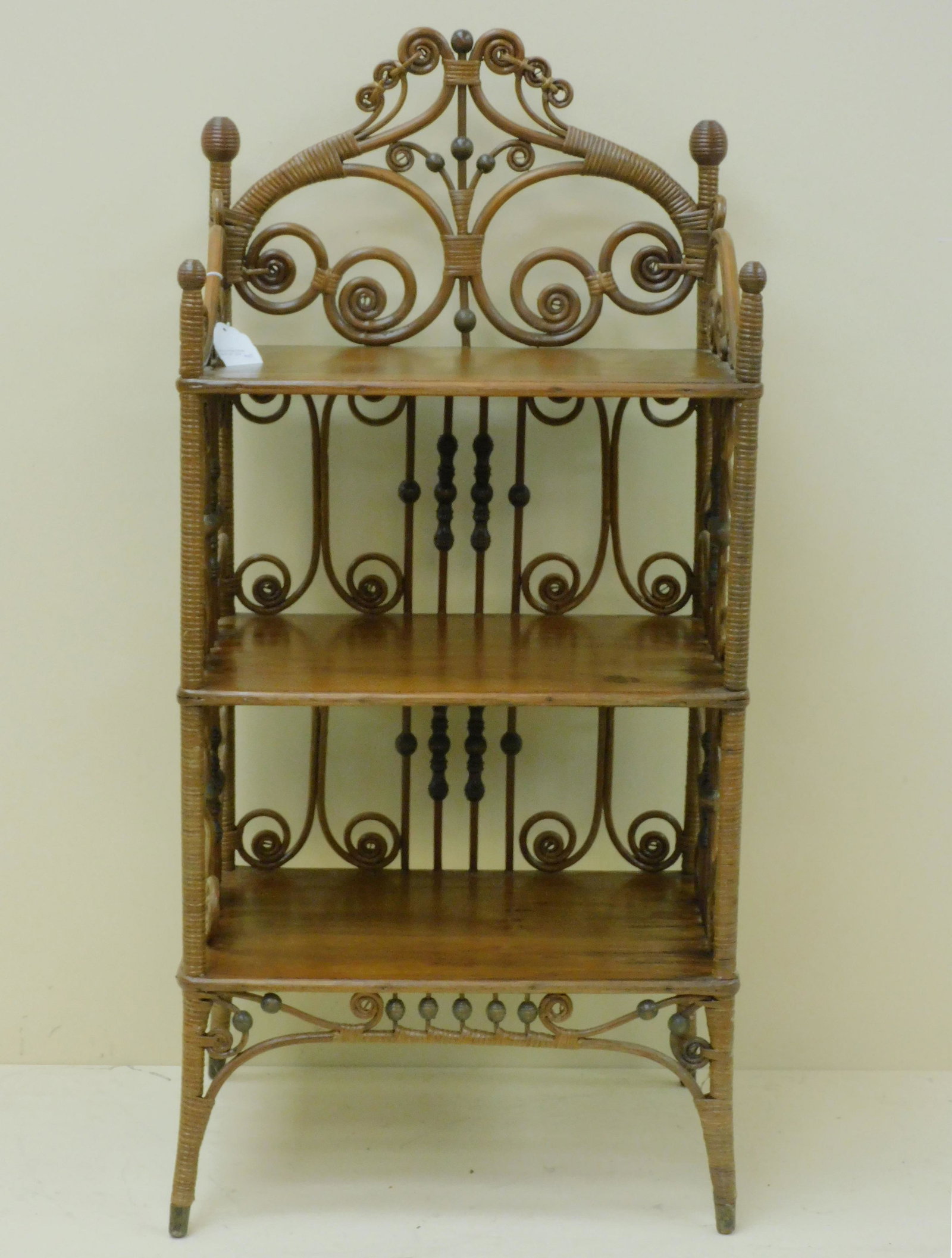 Victorian wicker music stand, Heywood Bros.: Wakefield Co., #6437 in the 1898 catalogue. Elaborate curlicue and beaded design. 3 shelves. Old natural finish. 37" high, 17 1/2" wide, 12 1/2" deep. Provenance: Mary Jean McLaughlin Collection.