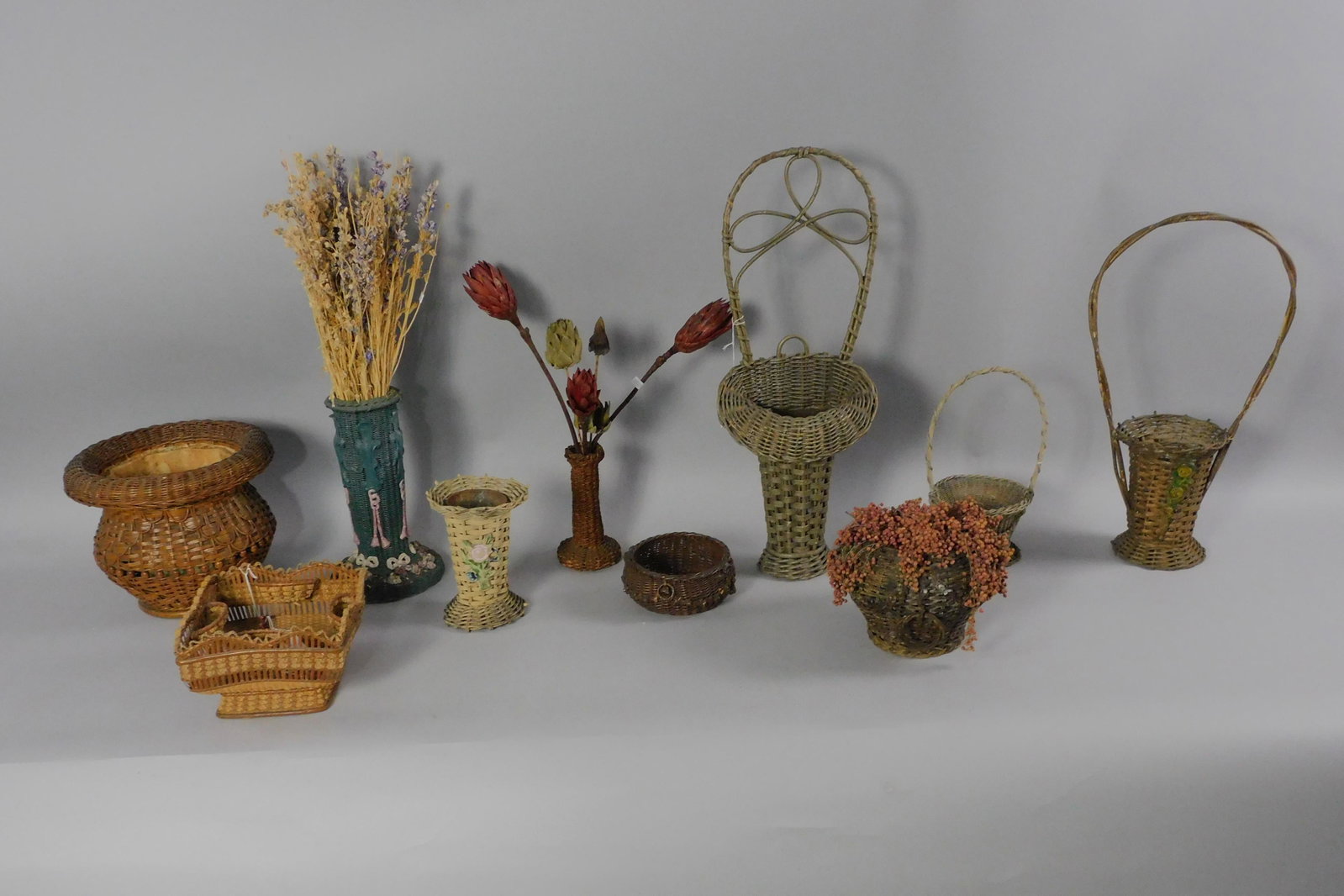 (11) Victorian wicker baskets, ranging in size: from 3" to 27" high. 2 3/4" to 12" wide. Some have applied gesso design, most are in original finish or paint. Includes wall hanging, sewing, vases, and other various types of baskets. Provenance: Mar