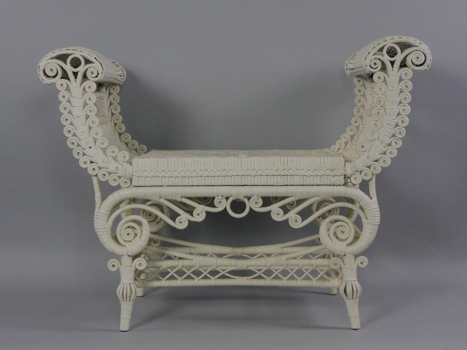 Victorian wicker Turkish style bench, late 19th: c. Rolled arms, curlicue trim, woven seat. Birdcage legs. Newer white paint. 27" high, 37" wide, 16" deep. Provenance: Mary Jean McLaughlin Collection .
