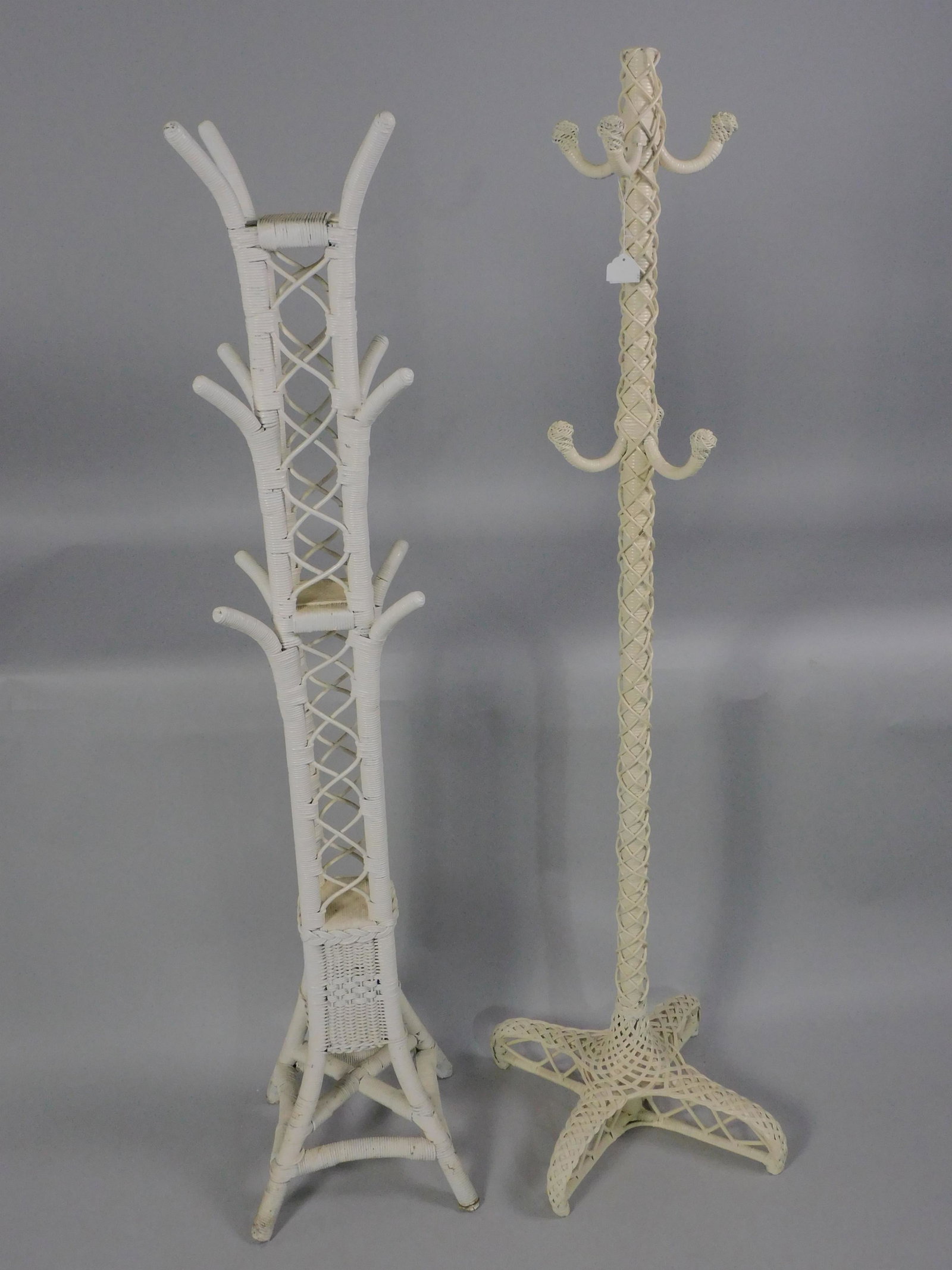(2) antique wicker coat trees, to include: 1): late 19th c., intricate loose braided design over the central pole, newer white painted finish, 66" high, 21" x 21" base, very good condition. 2) art deco, ca. 1920, geometric woven design, newer whit