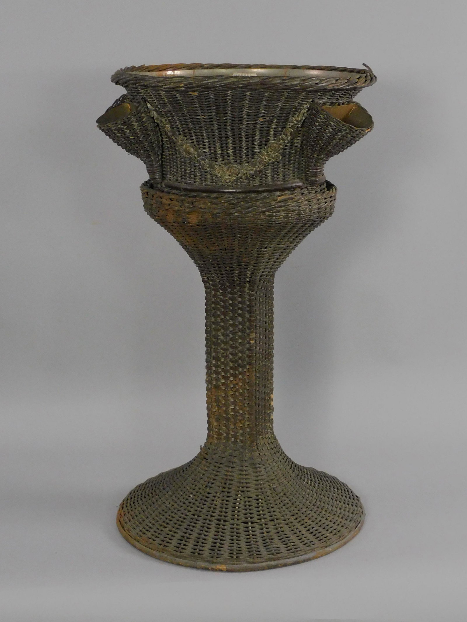 Rare wicker lighted fountain, ca. 1915. Old: natural finish with applied floral gesso decoration. Circular electrified top, three side pockets, pedestal base. Needs rewiring. Finish shows wear. 35" high, 19 1/2" top diameter. In two parts. Prove