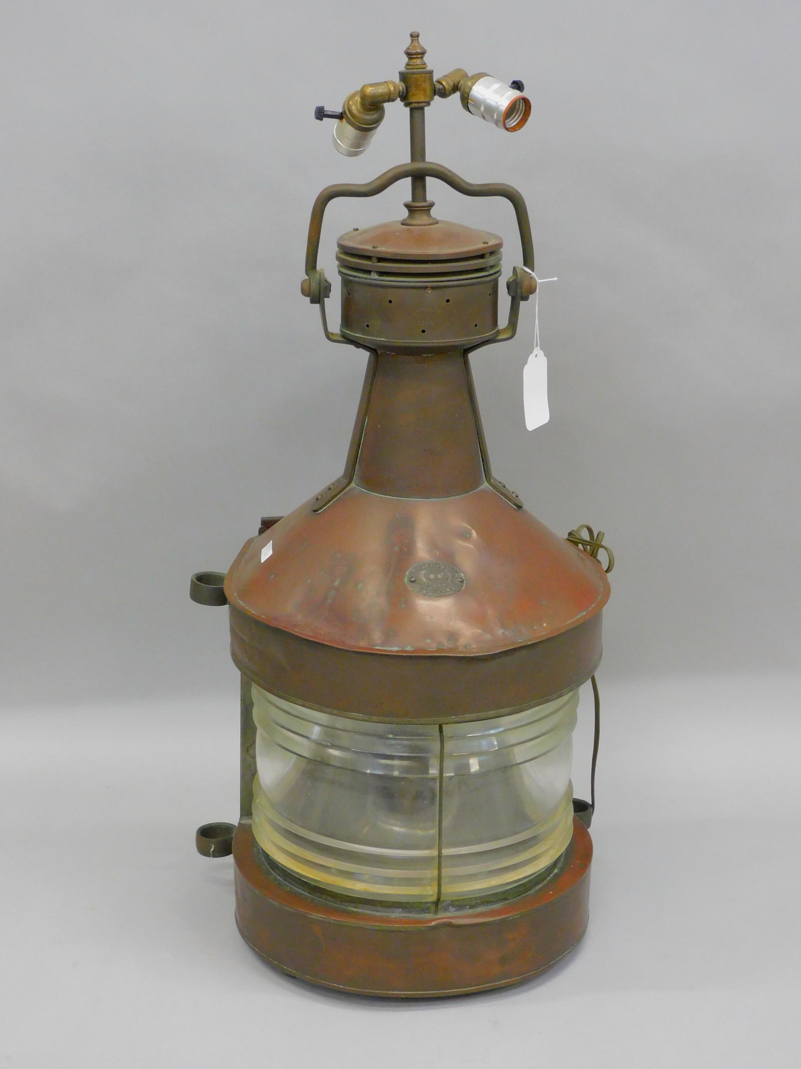 Copper ship's lantern. Early 20th c. William: Harvey & Co, Glasgow. Clear lens. Retains original oil font. It's been fitted as an electric lamp. Swing handle. Shows some dents. Old patinated finish. 28" high x 15 1/2" wide. 12 1/2" deep lamp heig
