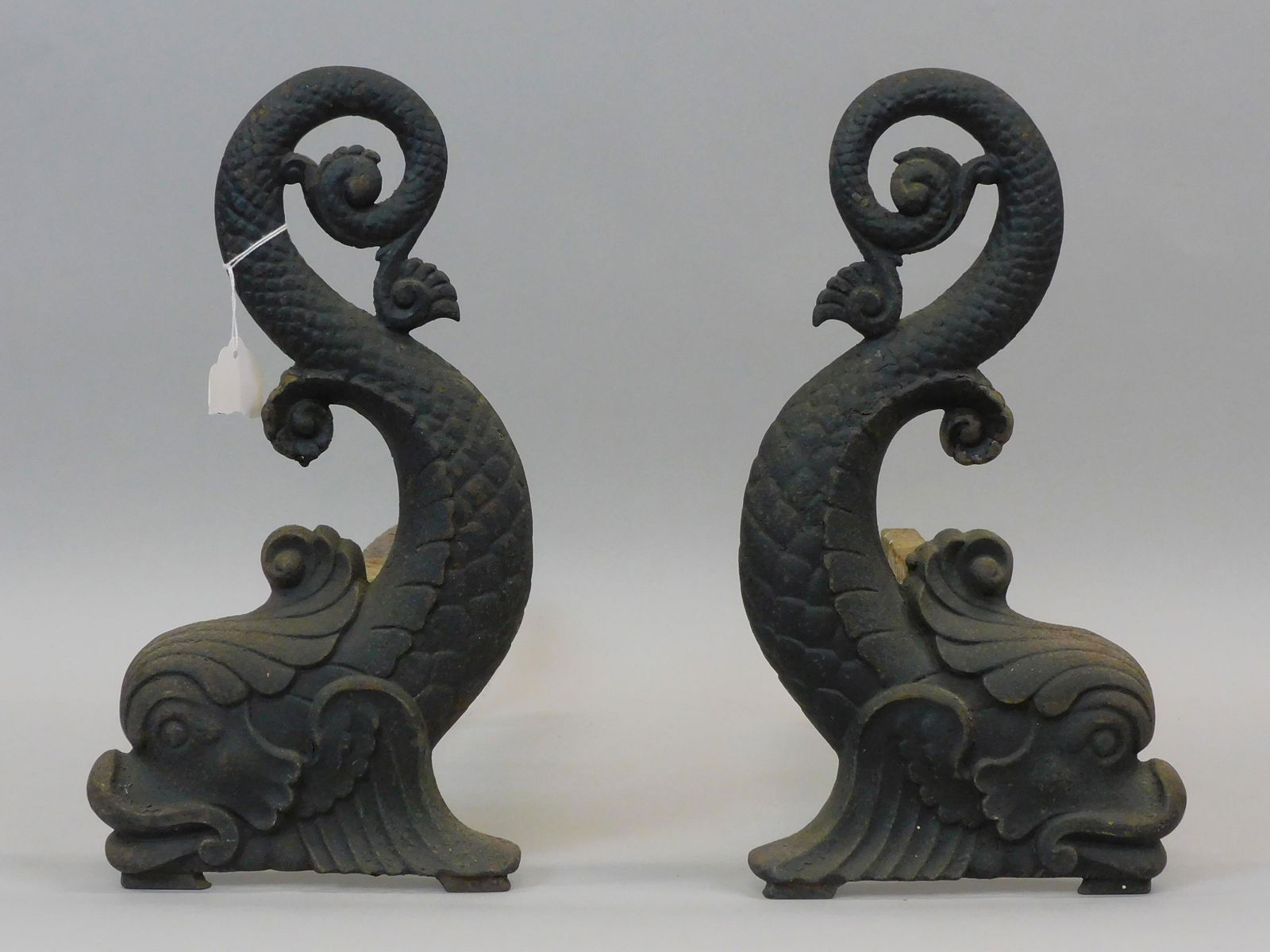 Pair of cast iron dolphin andirons. Late 19th: century. Signed Bradley & Hubbard. Slot in dog design. 14" x 7" x 16 1/2". Worn black painted finish. One dog shows bend.