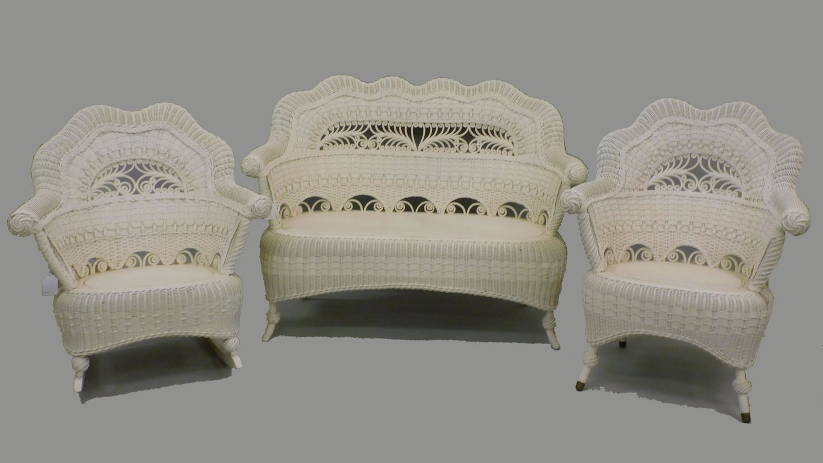 Rare (3) piece Victorian parlor set. Circa 1898.: Heywood Brothers & Wakefield Company. Modern white paint. To include, an armchair measuring 36" high, 29" wide, and 20" deep. A rocker measuring 35" high, 31" wide, and 29" deep. A settee measures 37"