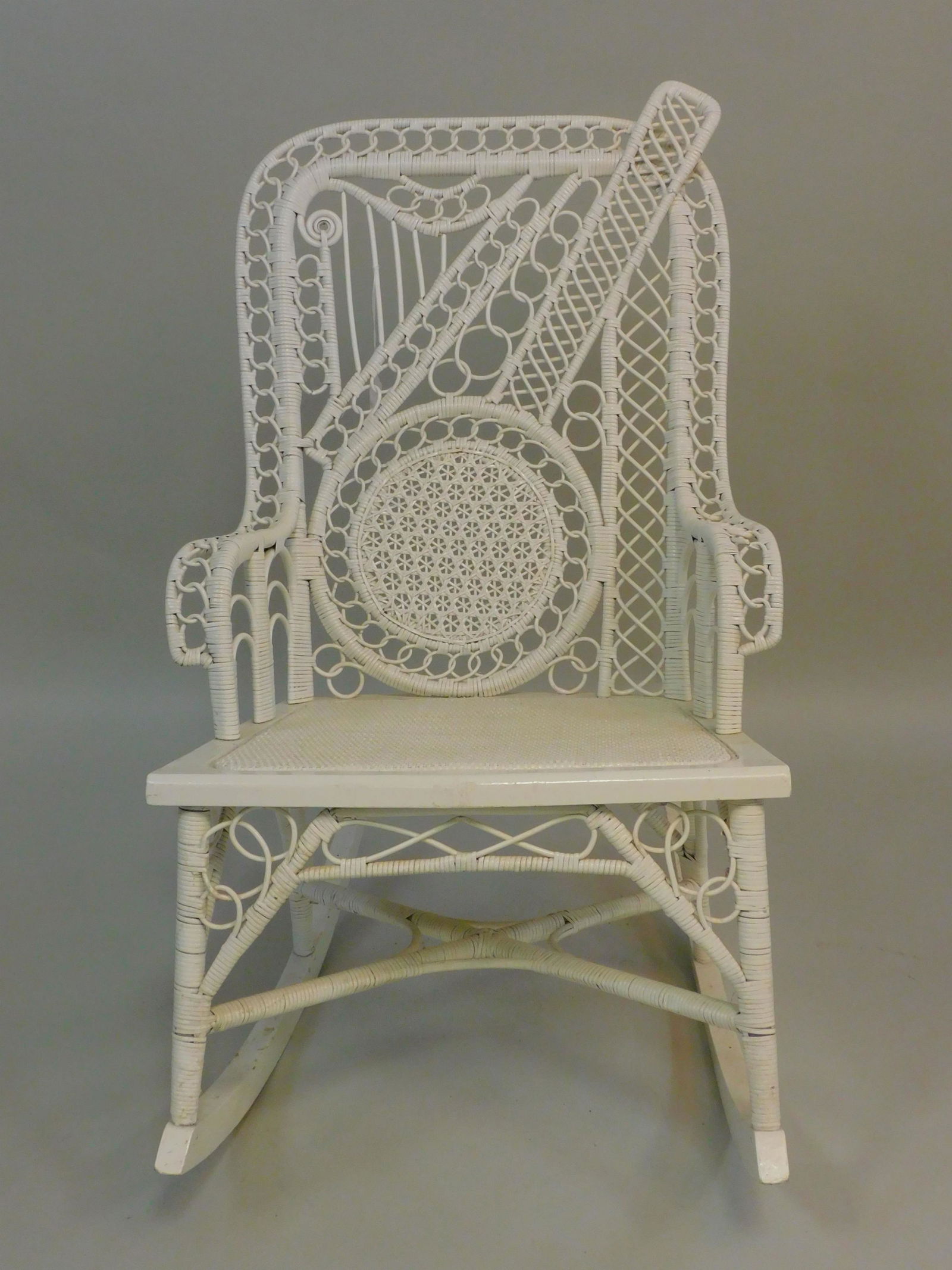 Victorian wicker theme-back rocker, ca. 1880.: Banjo and harp motif woven into the back, old white painted finish, good condition. 35" high, 20" wide, 17" deep. Provenance: Mary Jean McLaughlin collection.