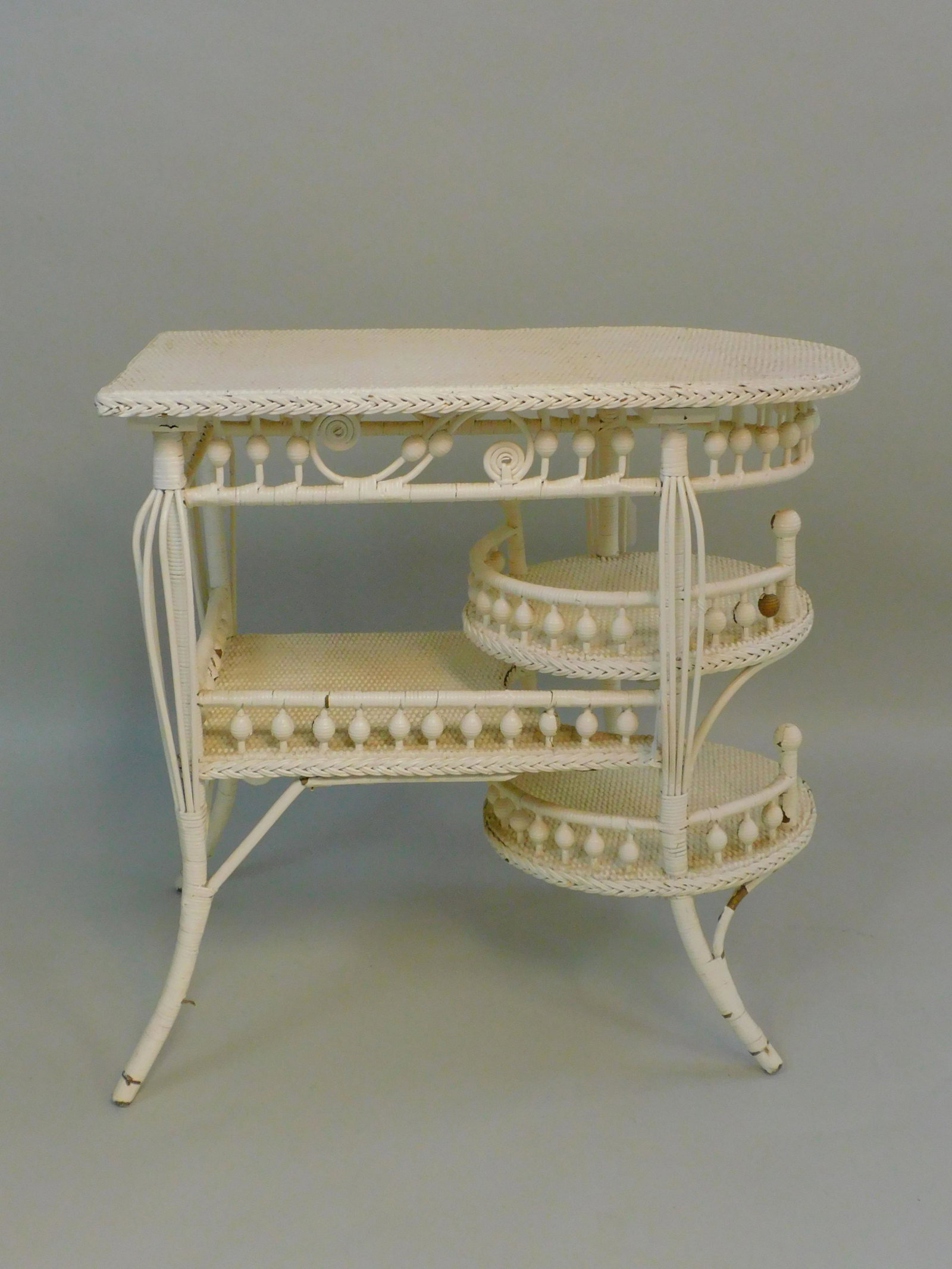 Victorian wicker occasional lamp table, ca. 1890.: Unusual multi-tiered design with bead and birdcage motifs. Old white paint. Good condition with some paint loss. 31" high, 31" wide, 18" deep. Provenance: Mary Jean McLaughlin collection.