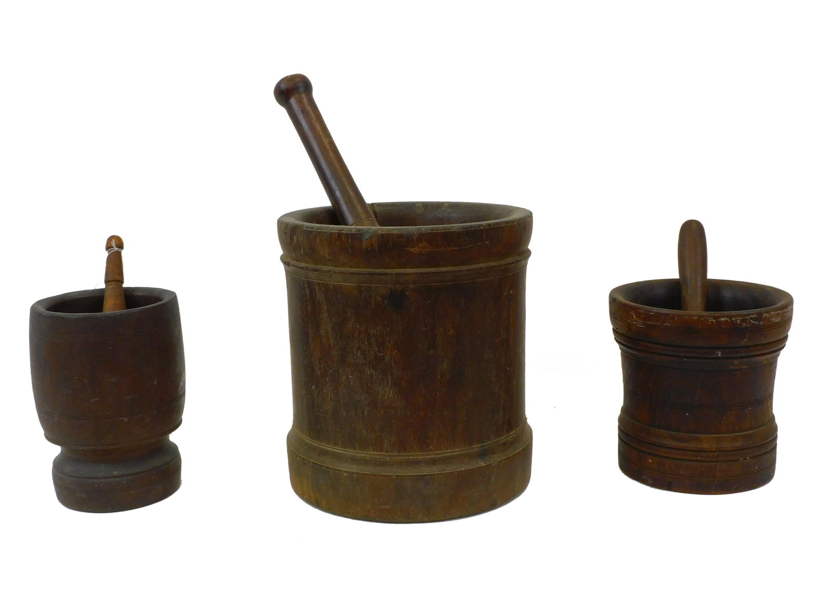(3) early mortar and pestles. 18th to early: 19th-century. To include: Large lignum vitae 12" high by 10 3/4" diameter. Smaller turn lignum vitae 8" high by 7 3/4" diameter. A turned maple, 8 3/4" high by 6 1/4" diameter.