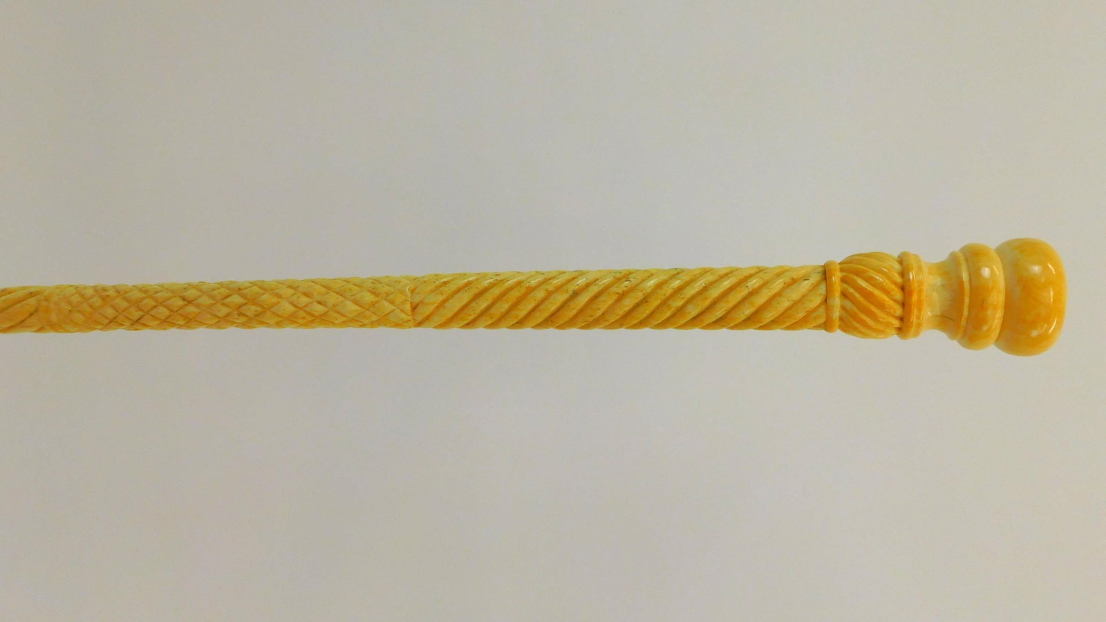 Fine Scrimshaw Walking Stick. 19th century. A: turned whale's tooth knob and carved panbone shaft with rope twist and repeating diamond pattern. 36" length. Very good condition. Deaccessioned from New Bedford Whaling Museum.