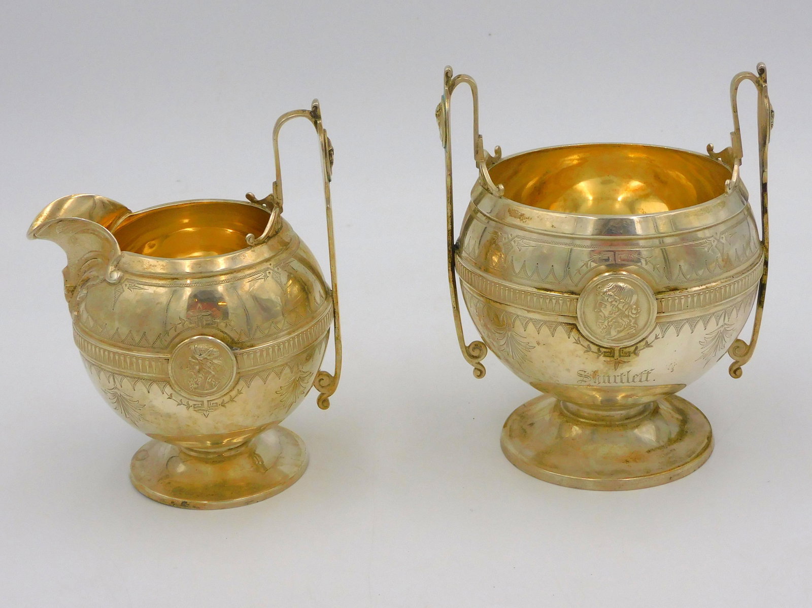 Gorham Medallion Pattern Coin Silver Creamer and: Sugar Bowl. Circa 1865. Made in Providence Rhode Island. Both are globular form with a plied band, centered by profile, portraits delicate handles with similar portraits, raised on pedestal feet, mono