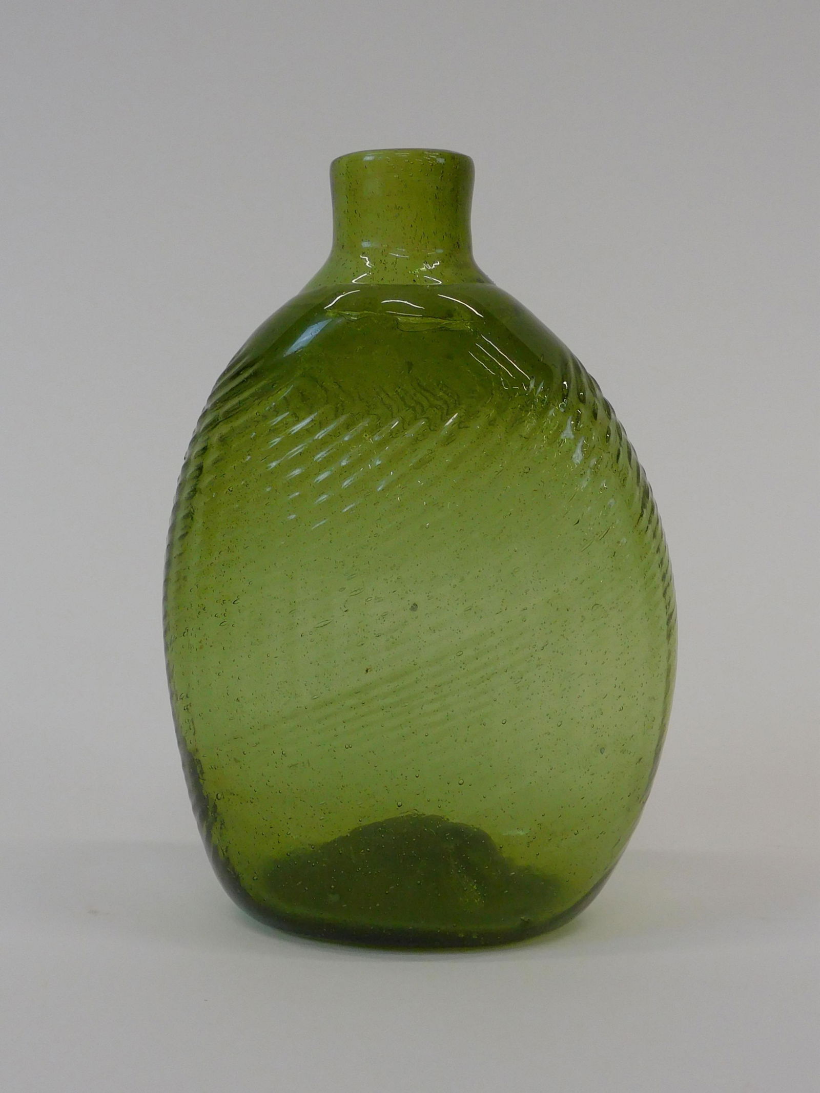 Pattern molded Pitkin type flask. Early: 19th-century. Pattern molded. Half pint. Light green. Probably New England. Kick up base with rough pontil. 5" high by 3 1/4" wide. Some high point wear. Shows several small potstones. Overall seems t