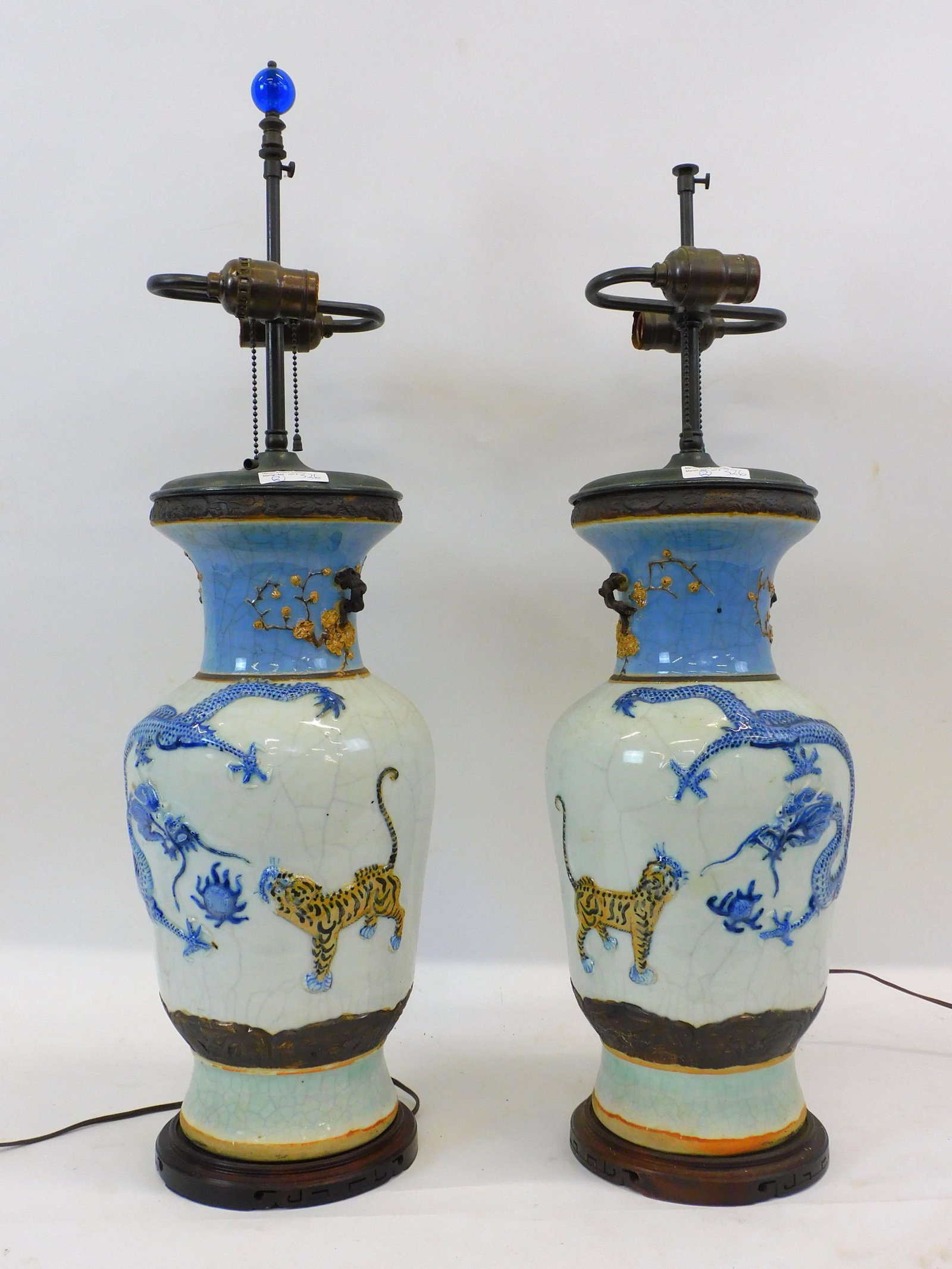 Chinese Export porcelain vases mounted as lamps.: With raised dragon and tiger motifs. Craquelure porcelain glaze. Vase height is 17 1/2" and 28" overall. Wired for American use. One is missing a blue glass ball finial.