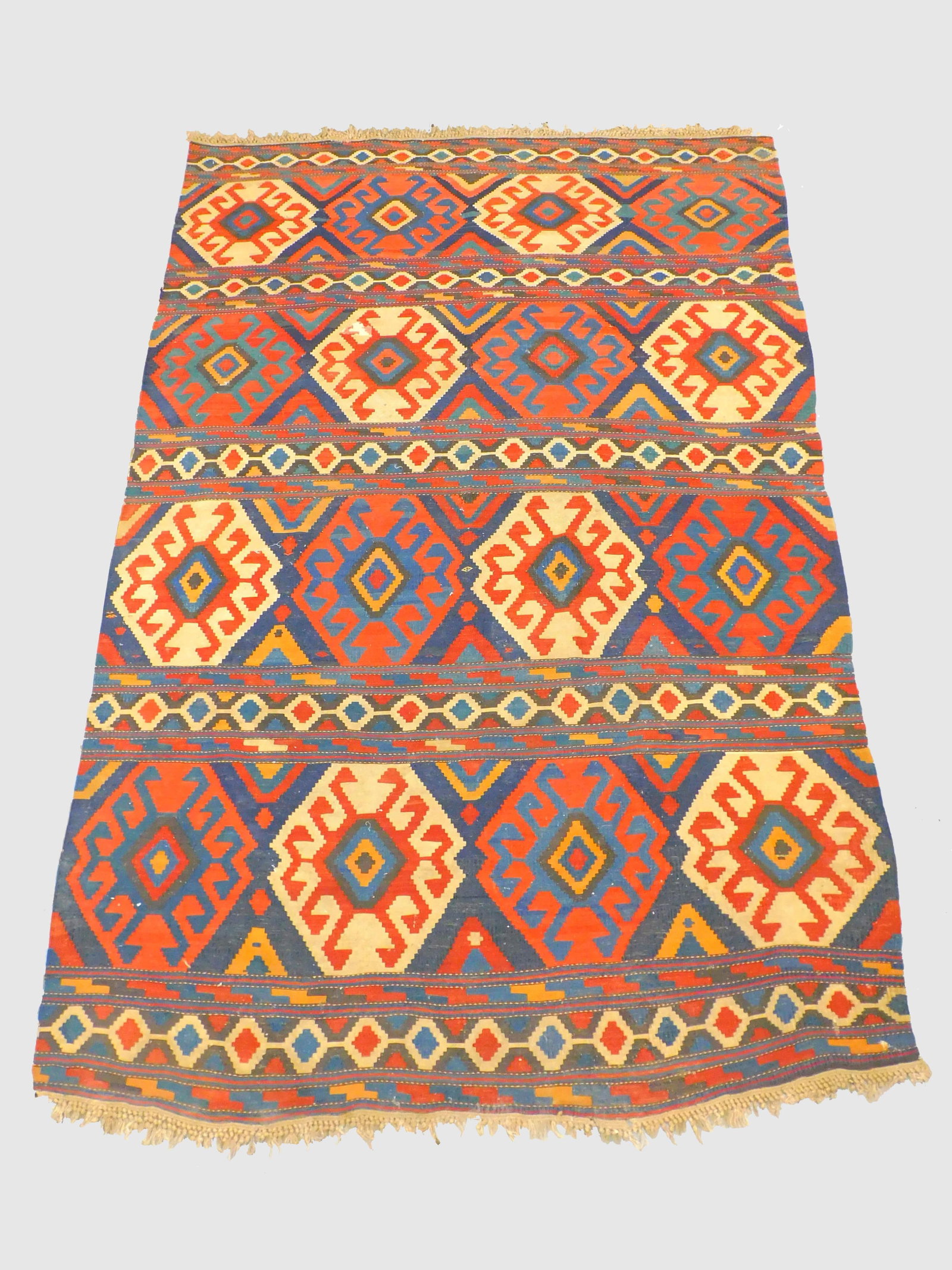 A Kilim Rug. Early 20th century. Geometric: designs, flat woven. 73" by 108". Shows some old repairs. Age appropriate wear.