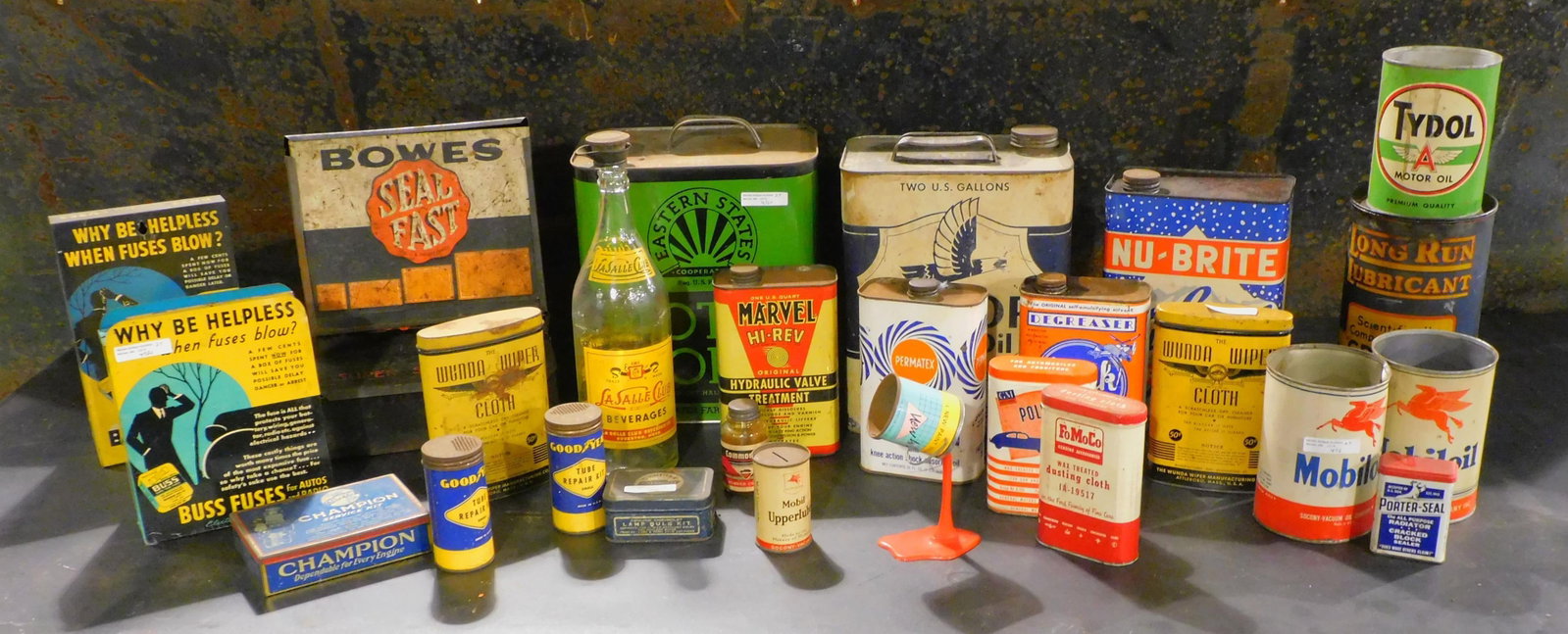 A collection of 25 automotive related: advertising, tins, and two glass bottles to include buss fuses, Champion service kit, Goodyear tube repair, LaSalle club beverages, GM polishing cloth, Mobil oil, long run lubricant, etc. ranging in s