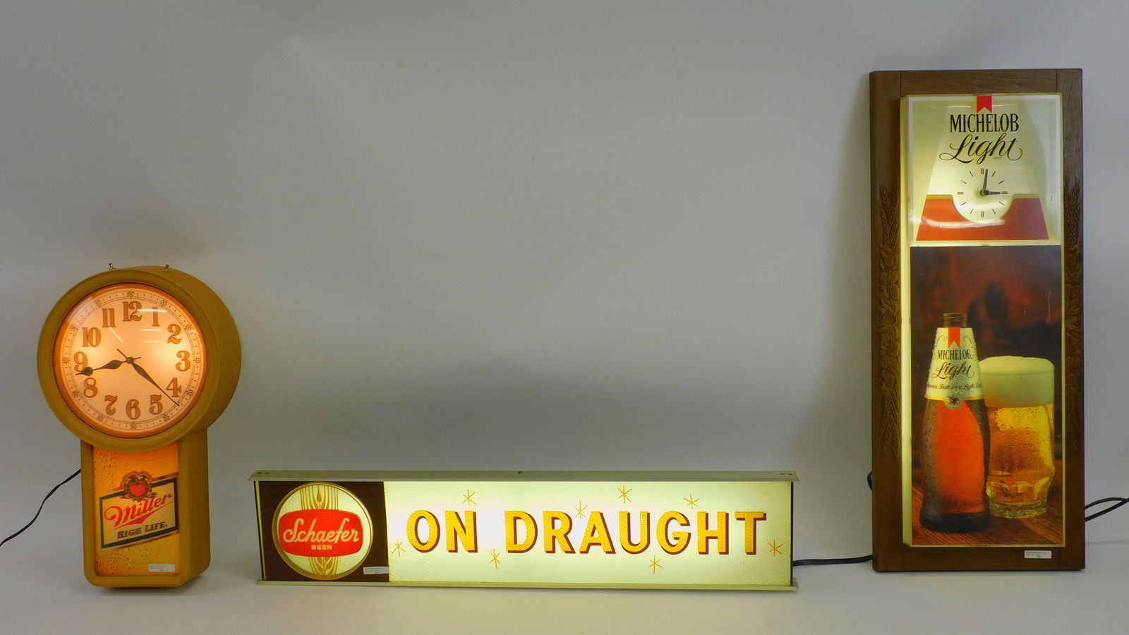 3 Breweriana advertising items to include a: vintage Miller Highlife clock. 21" high 12 1/2" wide 4 1/2" deep, working condition. A Michelob Light illuminated advertising clock, working condition, 33 1/2" high by 14" wide by 5" deep. Shows chip