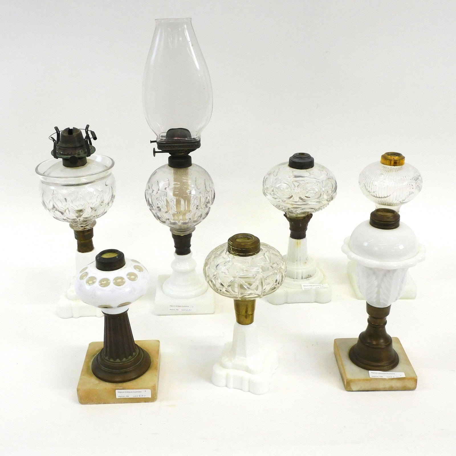 (7) fluid lamps. 19th century. To include: 9": reeded bell flower with an opalescent base. 9" lamp with opalescent base. 7 1/2" lamp with cut overlay font and brass and marble base. 17 1/4" lamp with thumbprint pattern font, opalescent base, and a