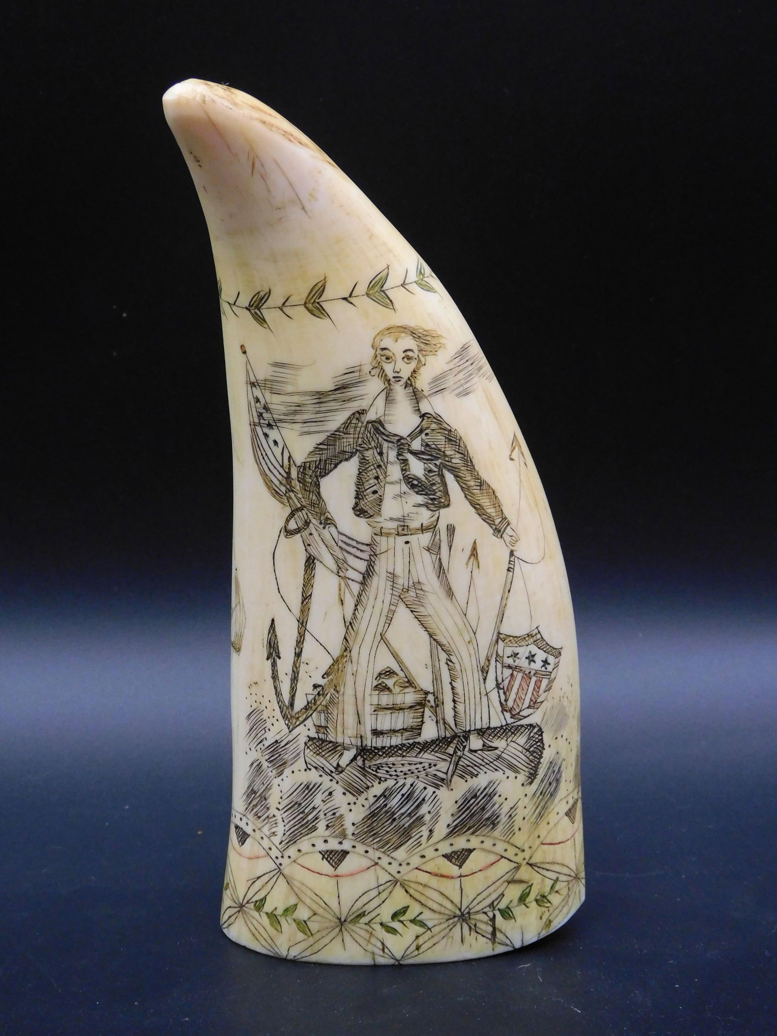 Scrimshaw Sperm Whale Tooth: 20th c. A finely engraved polychrome sperm whale tooth. Recto: Features a Jack Tar sailor with American flag harpoon and other tools. Verso: Shows a whaleship under sail with sperm shales in a flurry.