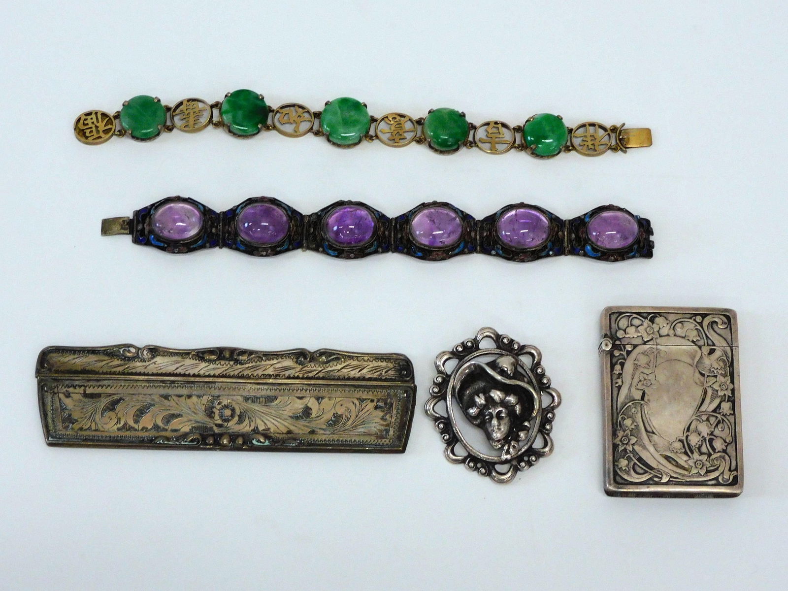 Lot Of Silver Jewelry: (2) Asian bracelets, 6 1/4" and 7" long. One with gold plate and jade stones. The other with amethyst cabochon and enamel. Ornate brooch with ladies head. Fancy match safe, 2 3/8" x 1 5/8". Engraved s