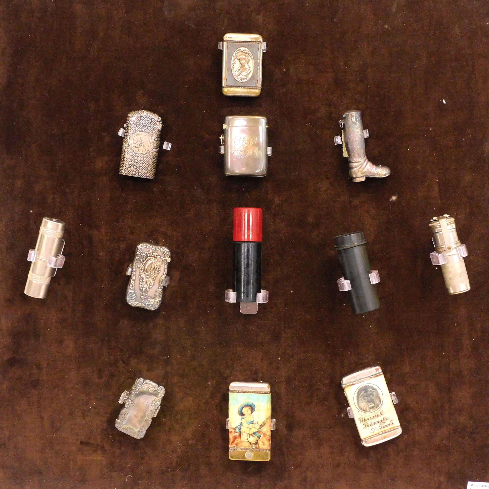 (12) Sterling Silver And Other Match Safes: To include: (5) English, French and Sterling Silver, one sterling silver boot shaped advertising and litho paper on tin. (2) Bakelite, one with compass. (2) Metal case match holders. In a gold framed