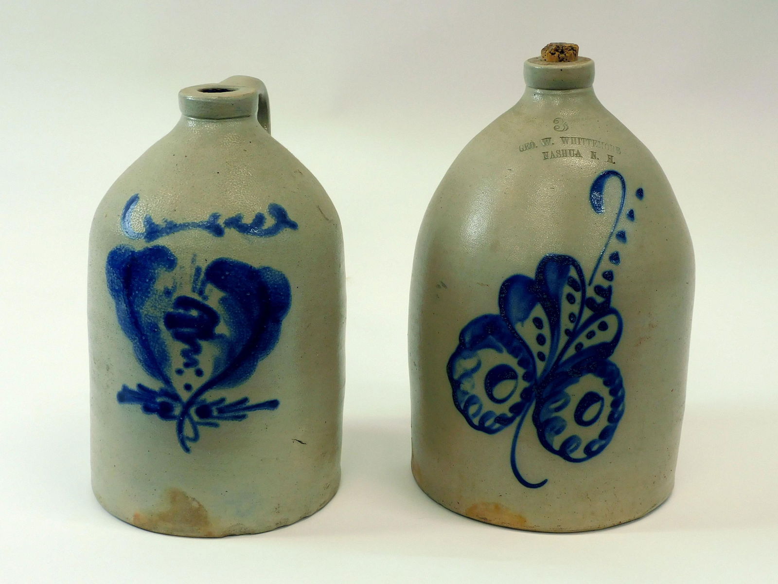 (2) Blue Decorated Stoneware Jugs: 19th C. To include: 3 gallon GEO.W. Whittemore Nashua, NH, approx. 15 1/2" high. Unmarked jug with large blue decoration, approx. 14" high.