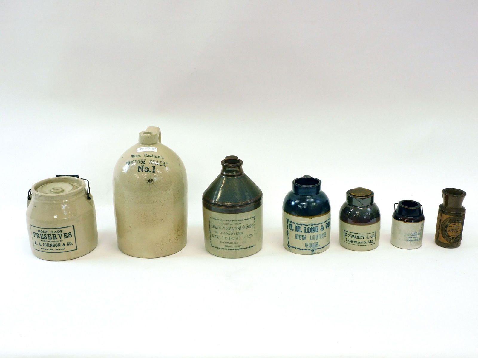 (7) Stoneware Advertising Jugs And Jars: To include: H A Johnson Preserves covered crock, 6" high. A Hiram Wheaton and Sons Imported New Bedford, Mass jug, 8 1/2" high. A C.M. Long and Company New London CT oyster jar, 6 1/2" high. Brown and