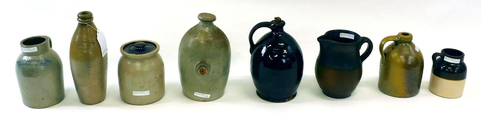 (8) Stoneware And Redware Jugs Etc.: To include: 9" high redware jug, good condition. 10" high M and R S Crabbie 26 Elm St. Boston oatmeal glazed flask, good condition. 7" high two-tone pitcher. 7" high jug. And 7" high oyster stoneware