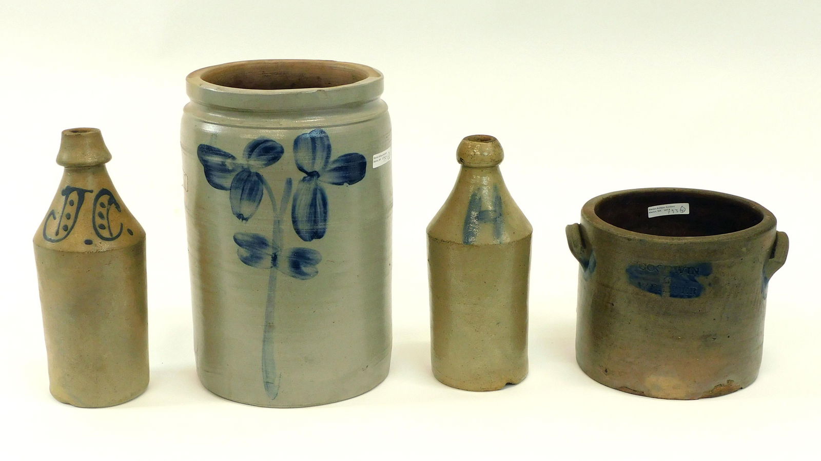 (4) Piece Of Blue Decorated Stoneware: To include: Crock with floral design, 12" high x 8" diameter. A Goodwin and Webster handled crock with blue trim, 6 1/2" high x 7 3/4" diameter. Beer bottle initialed J C., 10 3/4" high. Another bottl
