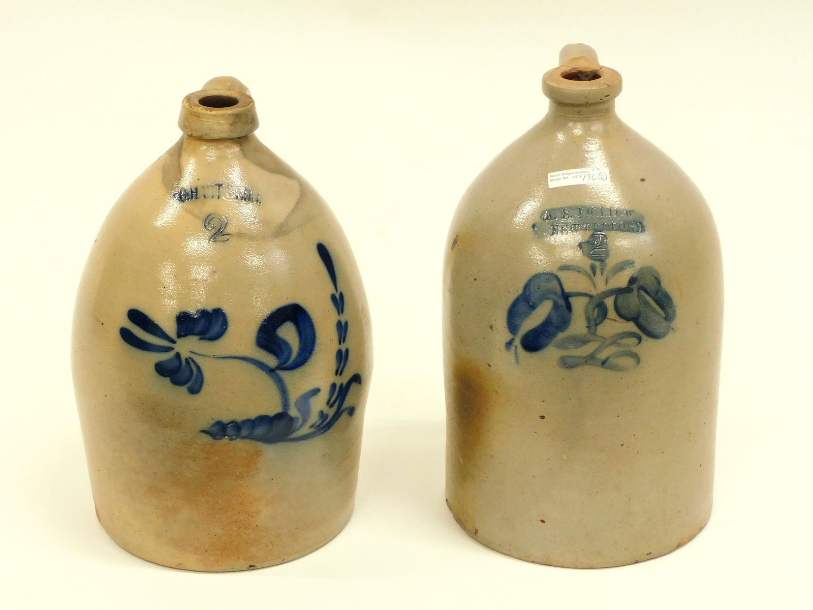 (2) 2-Gallon Blue Decorated Stoneware Jugs: C. Heart & Son 13 1/2" high. Shows some staining. A.S. Bigelow, New Bedford 14 1/2" high. Handle shows repair.