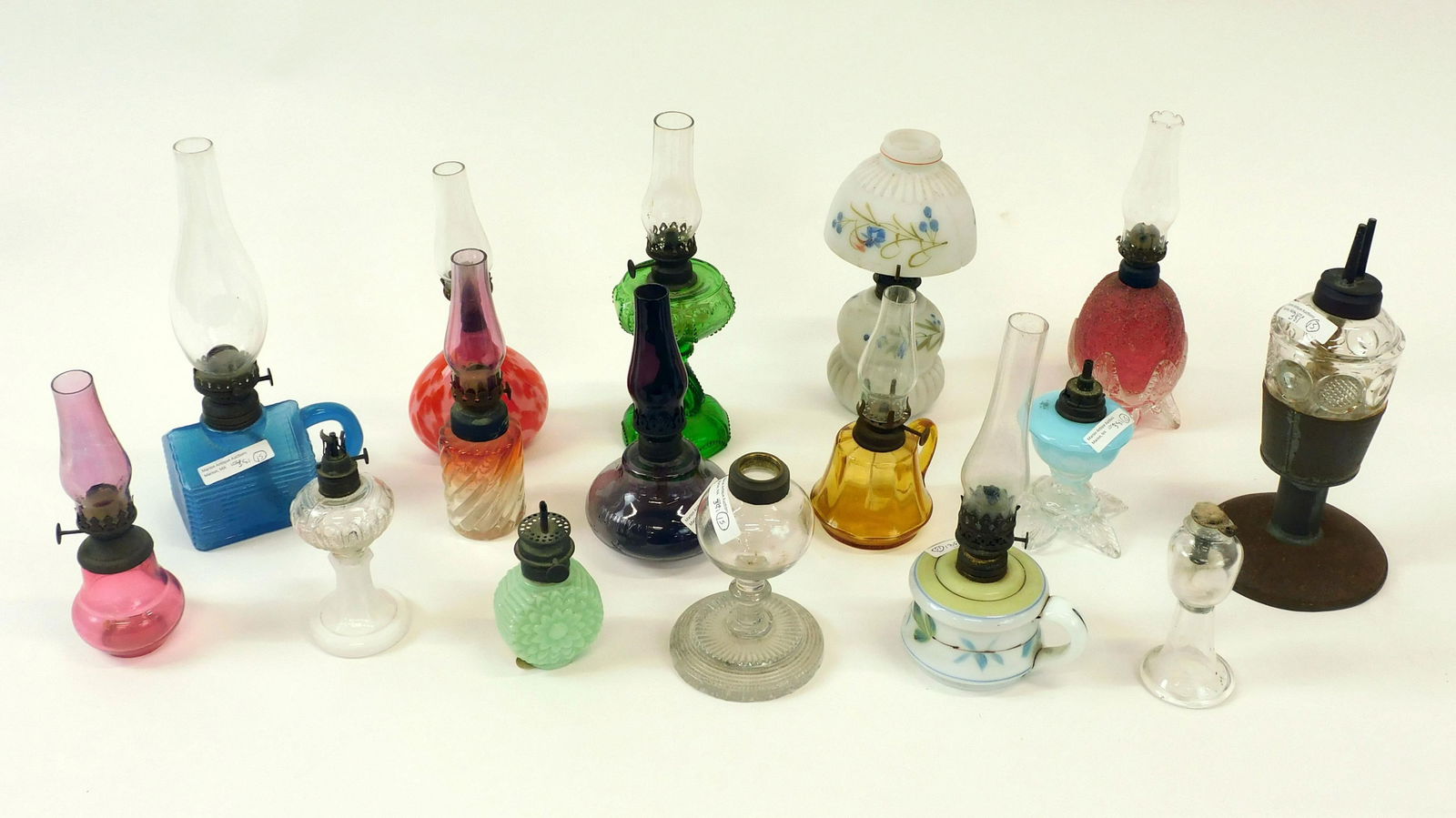 (15) Miniature Oil Lamps: 19th / 20th c. To include log cabin finger lamp, painted satin glass with cracked shade, Amethyst twinkle, red overshot with applied base with minor roughness, Rubina Baccarat swirl, early cup plate b