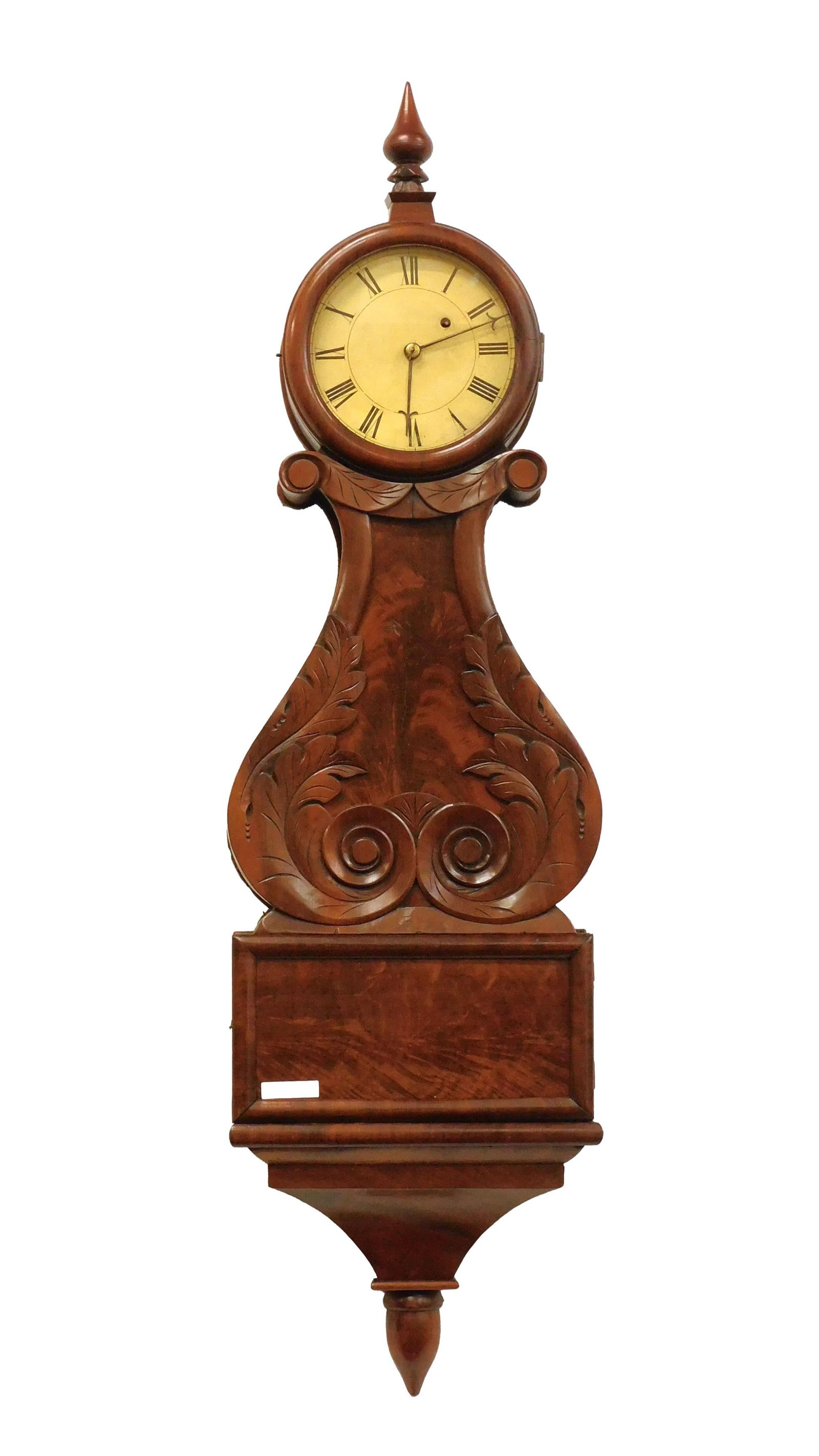Classical Lyre Clock Boston: Ca. 1830. Mahogany case. Box form. Grained panels. Scroll and foliate carved throat. Baluster finial above a turned mahogany bezel. Metal dial with Roman numerals. Bracket with drop acorn finial. Come