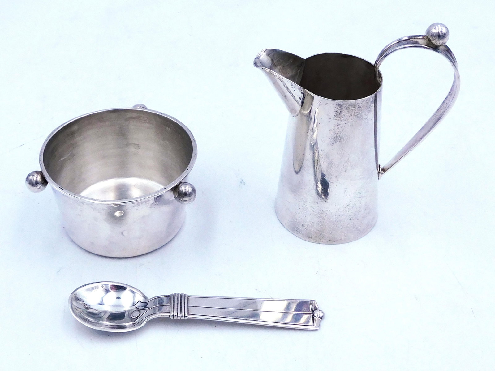 William Spratling Sterling Silver Pitcher and Bowl: 20th century. Taxco, Mexico. Includes spoon that is in the Amarres Disco pattern 1951-1956. Cream pitcher 3 1/2" high; sugar bowl 1 1/2" high; spoon 3 3/4" long. Total weight 4.05 ozt. Good condition.