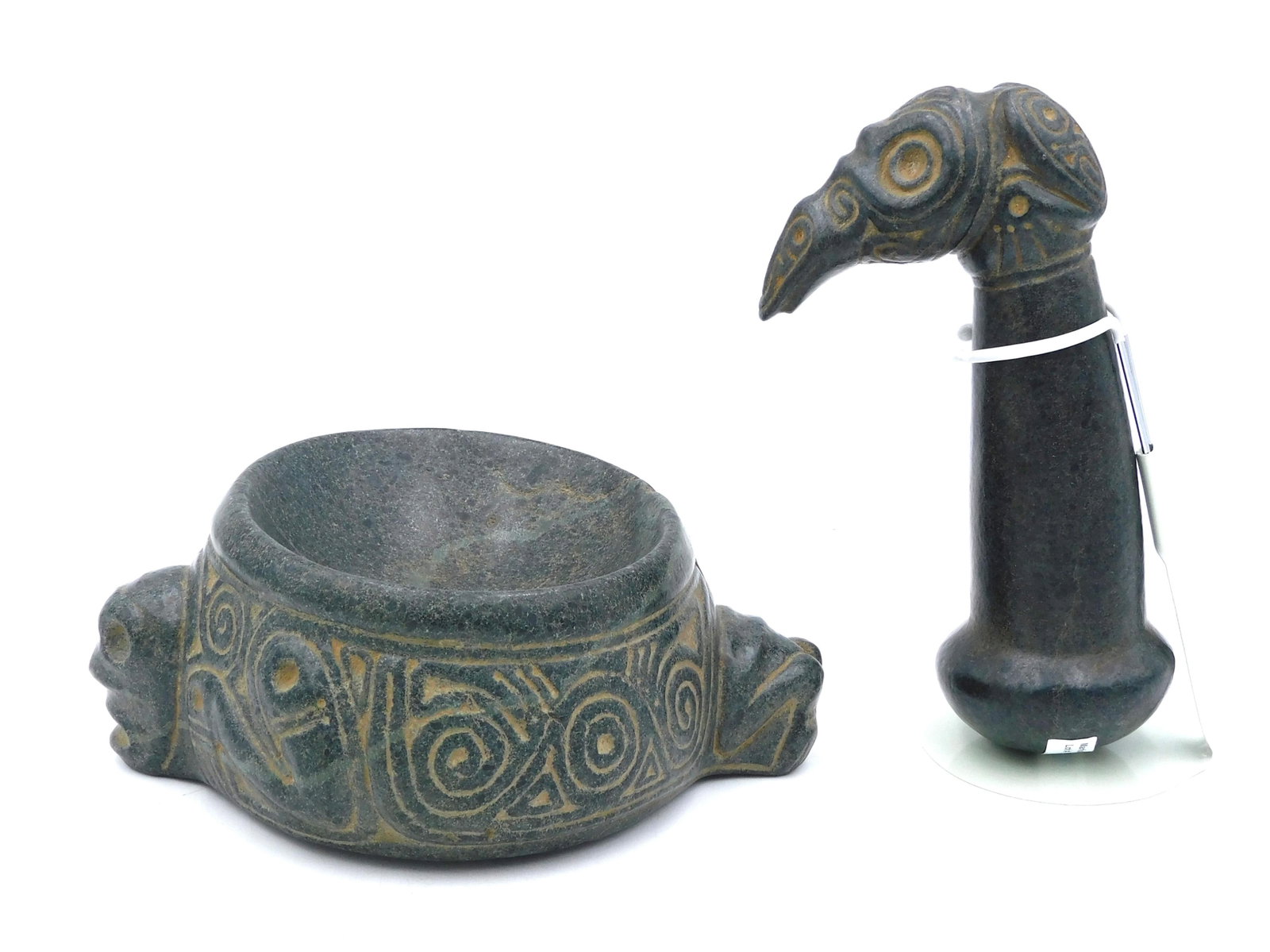 Taino Shaman's Mortar & Pestle: Circa 1200-1500 AD. Ironstone or basalt. Anthropic mortar and bird pestle, possibly a unique set. The mortar depicts the head of a shaman whose feet extend from the opposite side of the bowl. His eyes