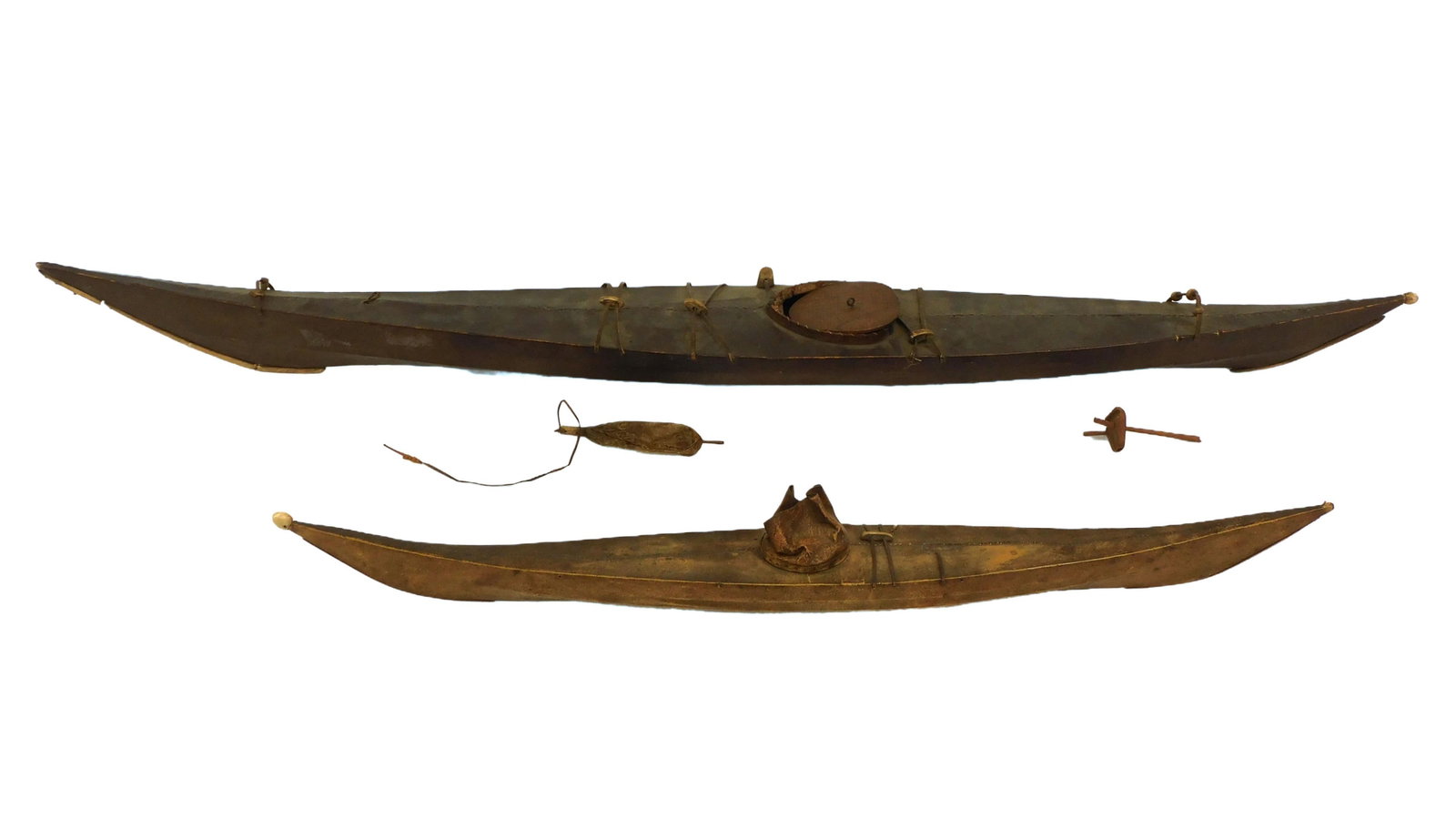 (2) Skin on Frame Kayak Models: Early 20th century. Two models of Inuit Greenland / Iceland kayaks. Sealskin on frame with bone trim, original informational labels and accessories. 27" long x 3" wide; and 41" long x 4 1/2" wide. Age