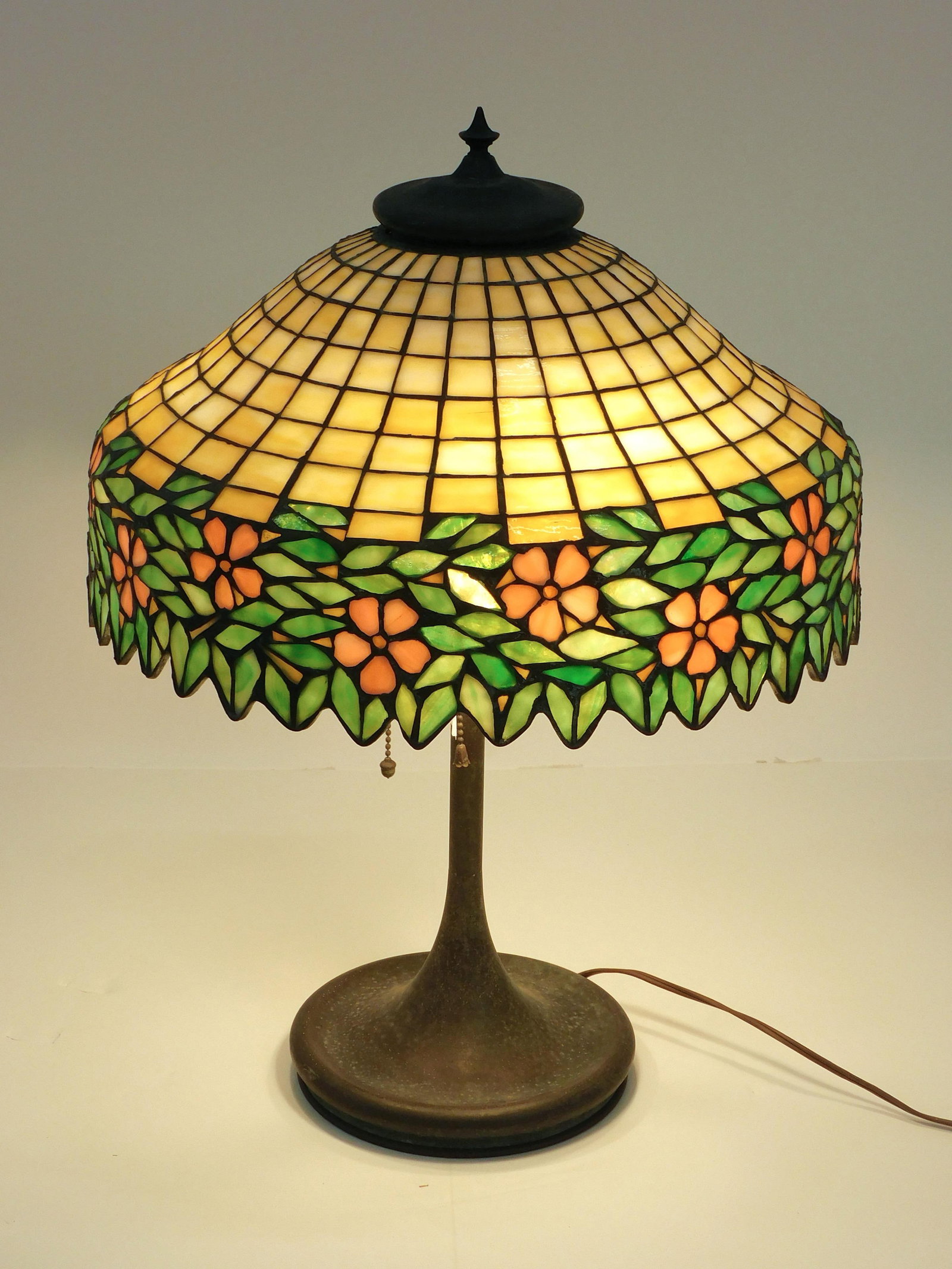Leaded Glass Table Lamp: Circa 1910. Unique Art Glass and Metal Company, Brooklyn, New York. Floral banded shade. 22" high x 16 1/2" diameter. Old rewired condition. One replaced socket. Otherwise in working condition consist