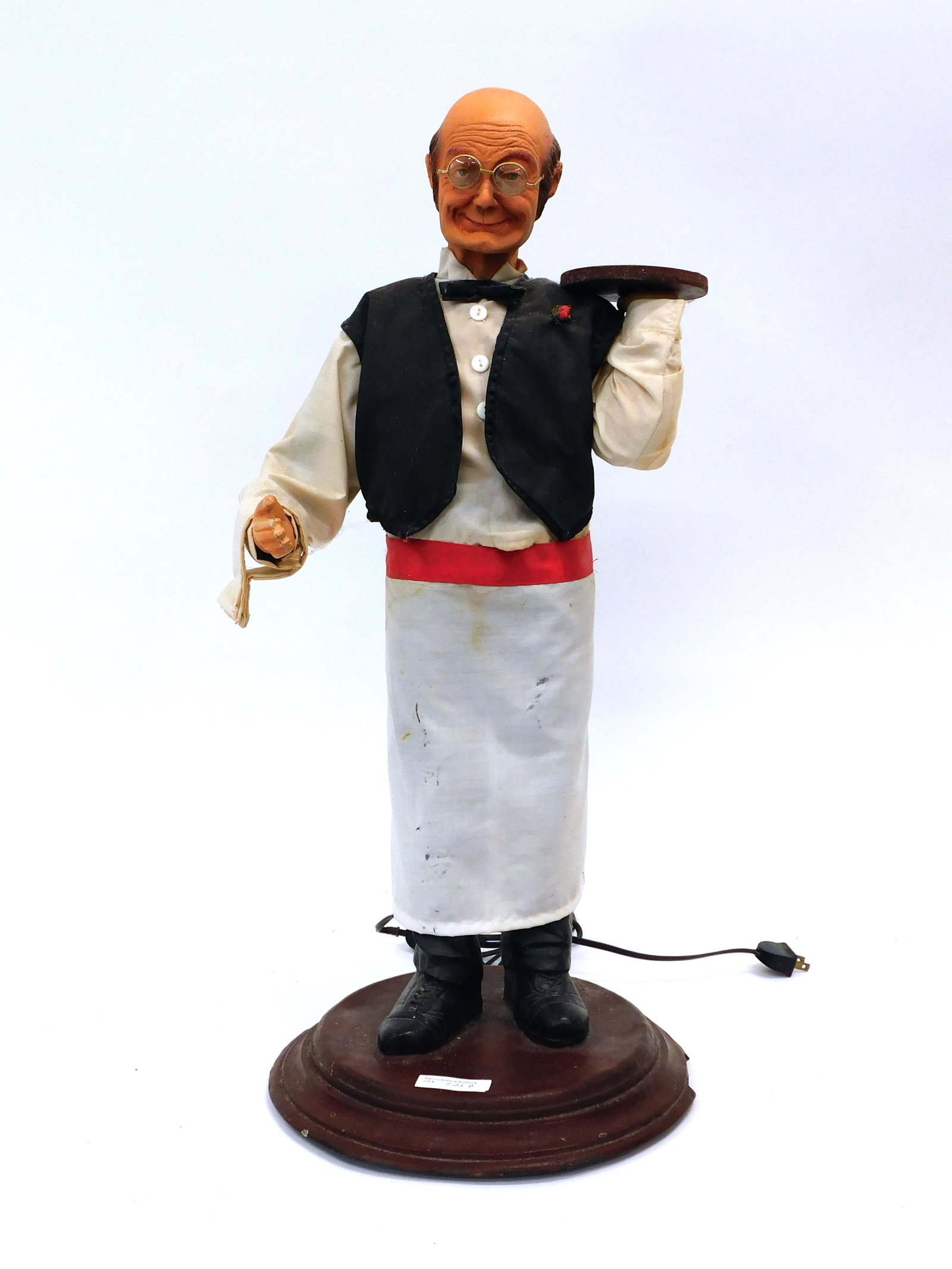Animatronic Waiter: 20th century. Plug in waiter with tray. His right arm moves and his head rotates. He is in working condition. 27" high x 11" wide x 12" deep. Shows some wear to the fingers and his uniform shows stain