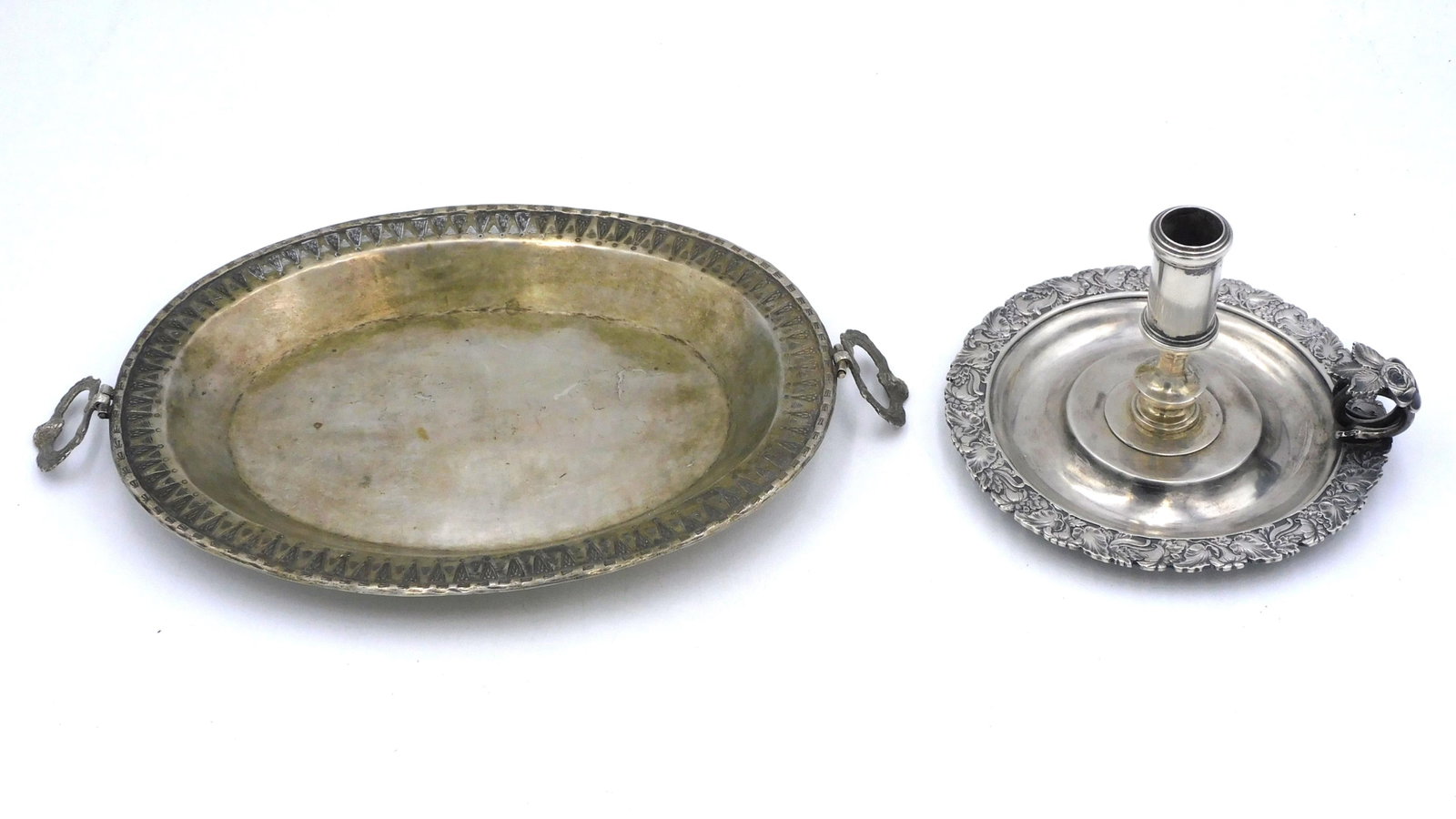 (2) Spanish Colonial Silver Pieces: 19th century. To include: A) Oval tray with swing handles. Handles decorated with faces. 13" wide x 8" deep. Good condition with age appropriate wear. 14.96 ozt. B) Unusual chamber stick with floral v
