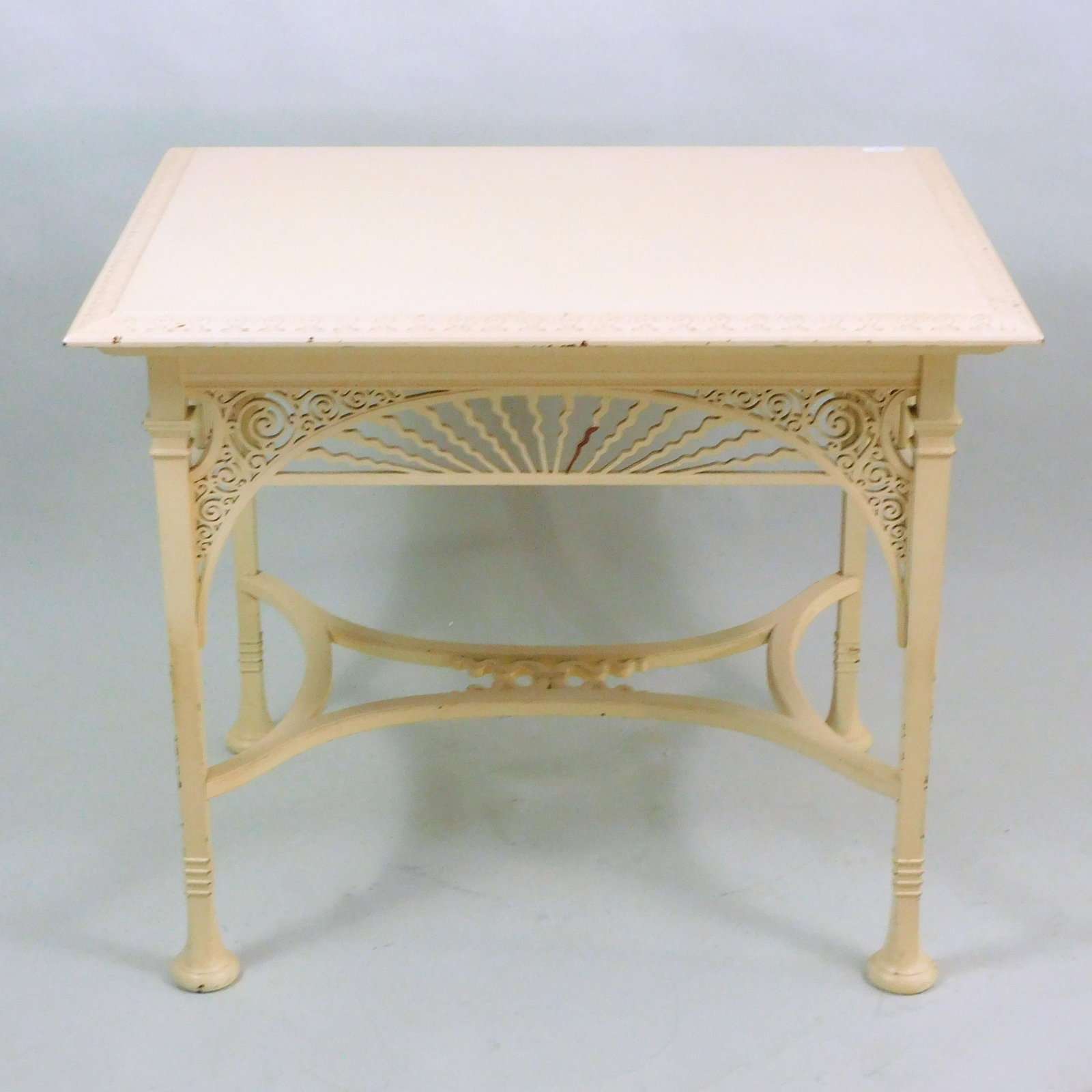 Victorian Center Table: Late 19th century. The table has a top carved border, ornate cut out skirt and a stretcher base, in white paint. 28 1/2" high x 34" wide x 26" deep. One missing piece of skirt and top shows crack. Pro