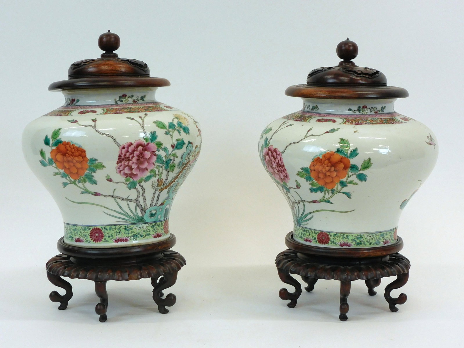 Pair of Chinese Export Porcelain Famille Vert Urns: 19th century. Carved hardwood stands and covers. Urns are decorated with birds, flowers and trees. Urns measure 9" high x 10" wide. With cover and stand they are 16" high. Overall good condition.