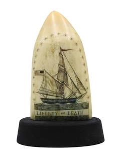 Scrimshaw Whale's Tooth by Robert Spring: (American, 1938-2016). Dated 1970. Polished and engraved polychrome tooth on stand. American sloop under sail with the title: "Liberty or Death". Verso features signature: "R Spring 70". 4 3/4"