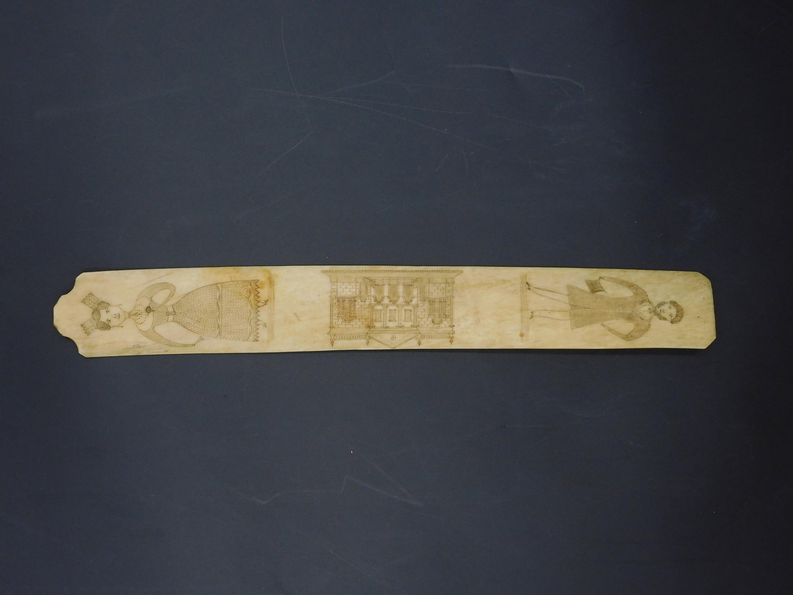 Scrimshaw Whalebone Busk: 19th C. Depicting a classical building or manor house flaked by a well-dressed man and woman. 13 1/2" long x 1 3/4".