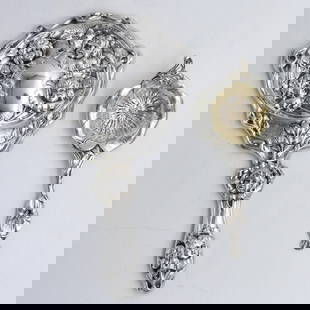 (2) Art Nouveau Sterling Silver Pieces: To include: (A) Weighted hand mirror. Cherub motifs throughout. 10 1/4" long x 6" wide. (B) Wallace tea strainer. Floral design. 7" long x 3" wide. 1.09 ozt. Provenance: A Newport, Rhode Island collec