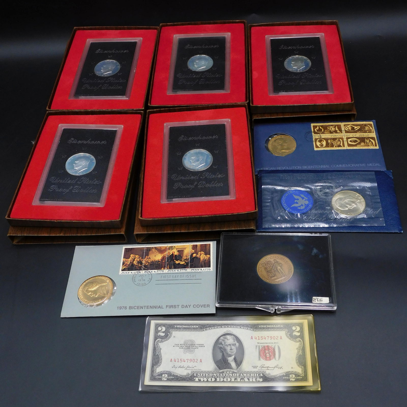 Collector Coin Lot: To include: (A) Six Eisenhower Silver Dollars (40%). Five are 1971 and one is 1973. (B) 1953 $2 bill. (C) Two Bicentennial First Day Covers with commemorative medals. (D) Uncle Sam commemorative medal